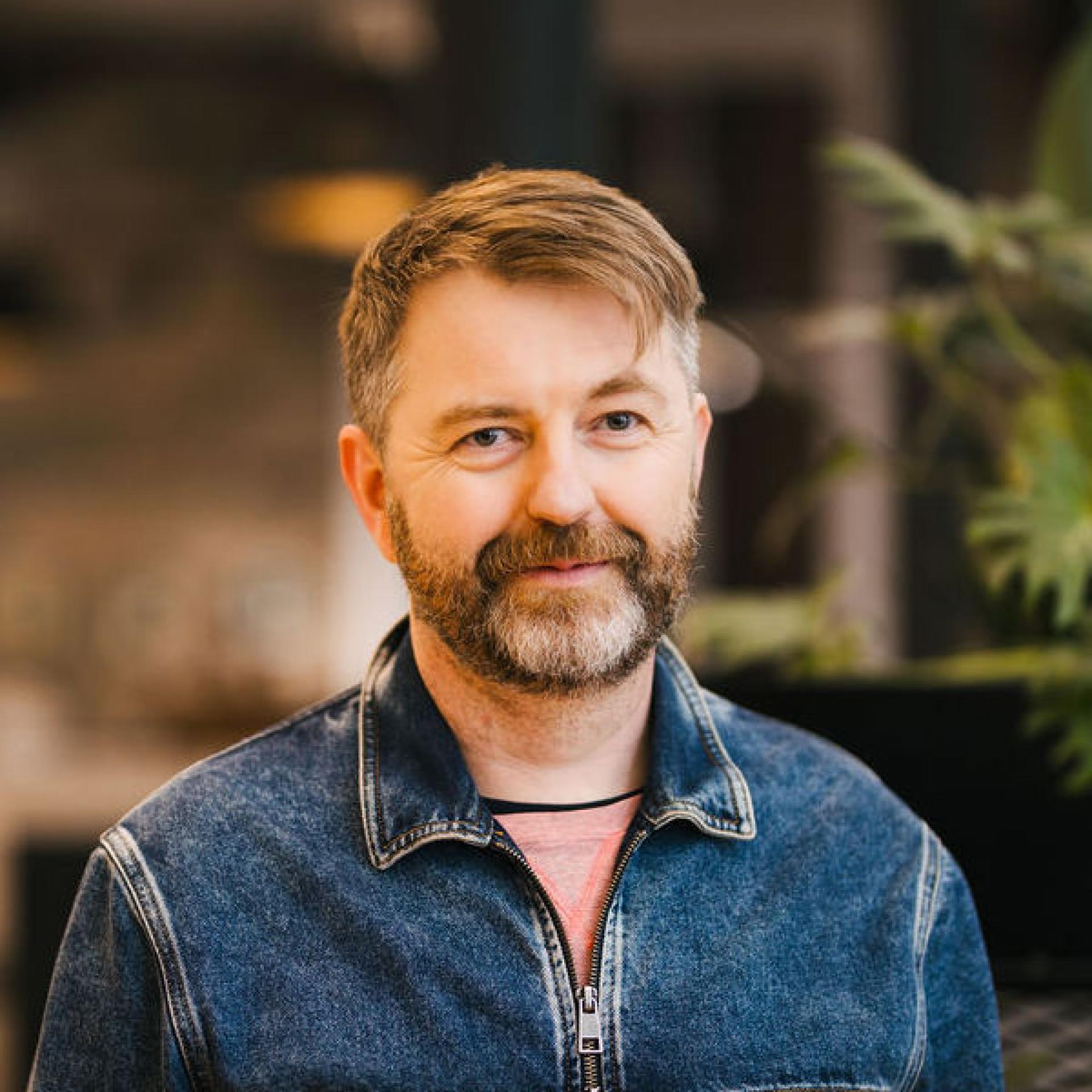 Professional speaker in a casual denim jacket discussing Glasgow's property market trends during a seminar.