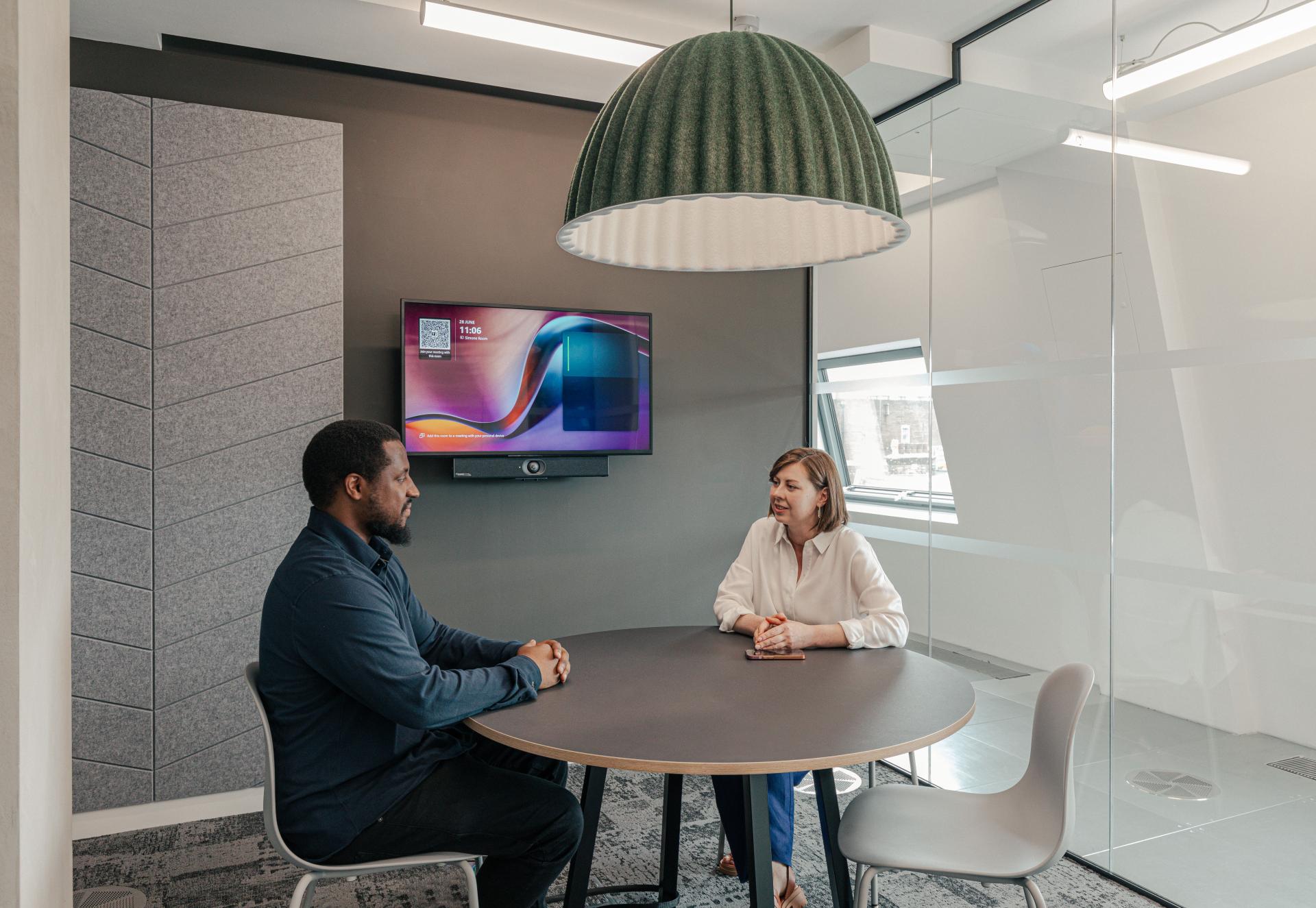 Collaborative workspace featuring Lacoste team members discussing ideas at a round table under a modern pendant light.