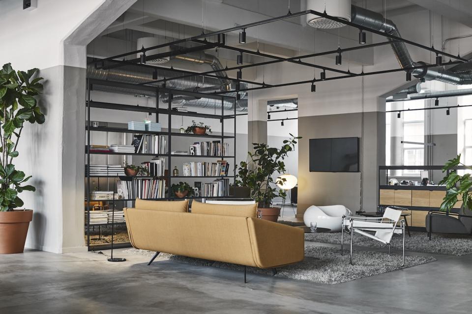 Modern interior design featuring a cozy seating area, bookshelves, and plants in a refurbished bread factory by Studio Joanna Laajisto.