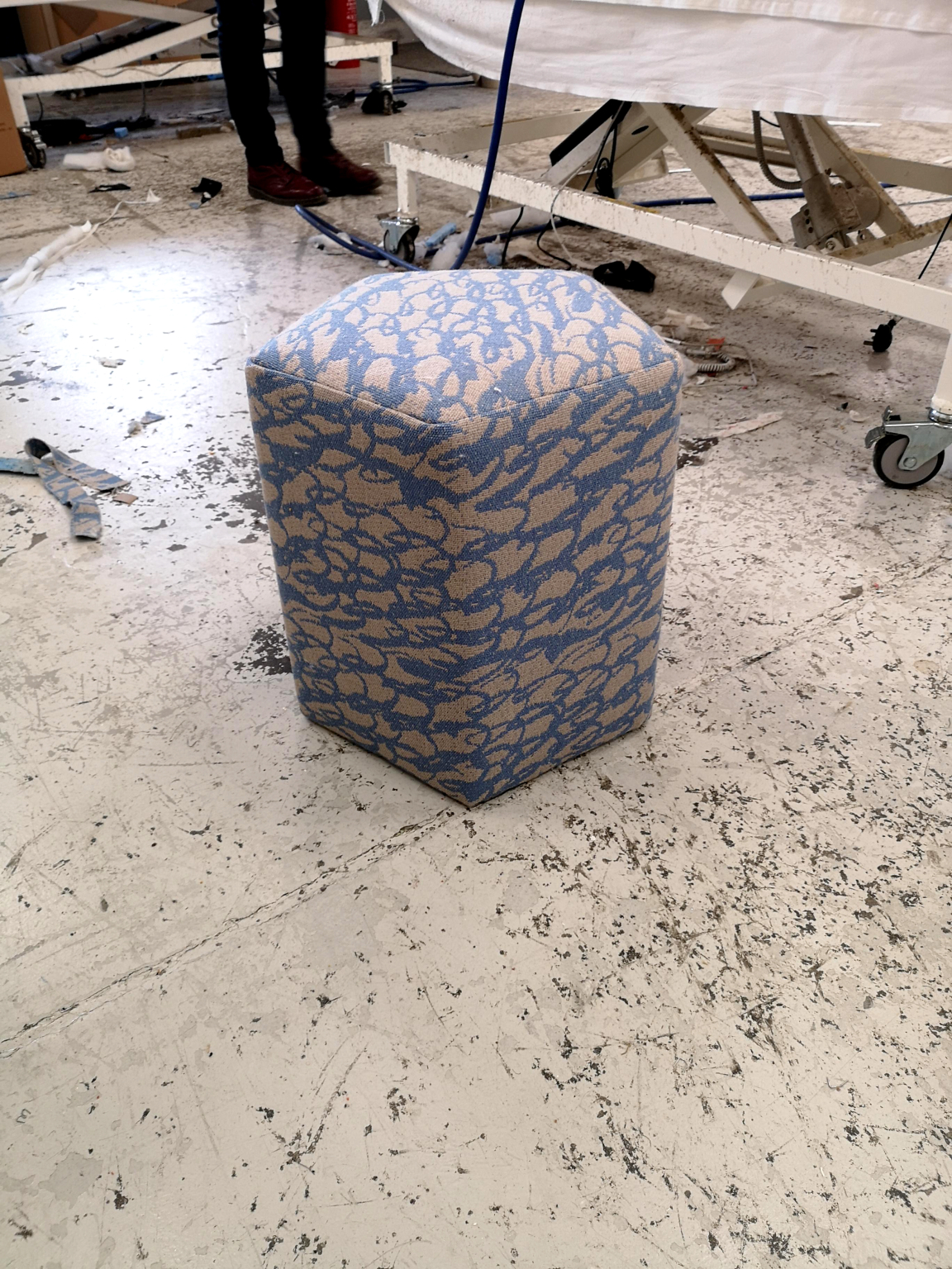 Wool-covered hexagonal ottoman in a workshop setting, showcasing sustainable British design and craftsmanship.