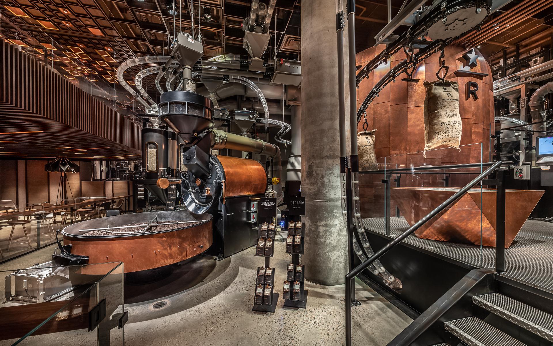 Inside Starbucks Reserve Roastery in New York, showcasing coffee roasting equipment and bags of imported coffee beans.