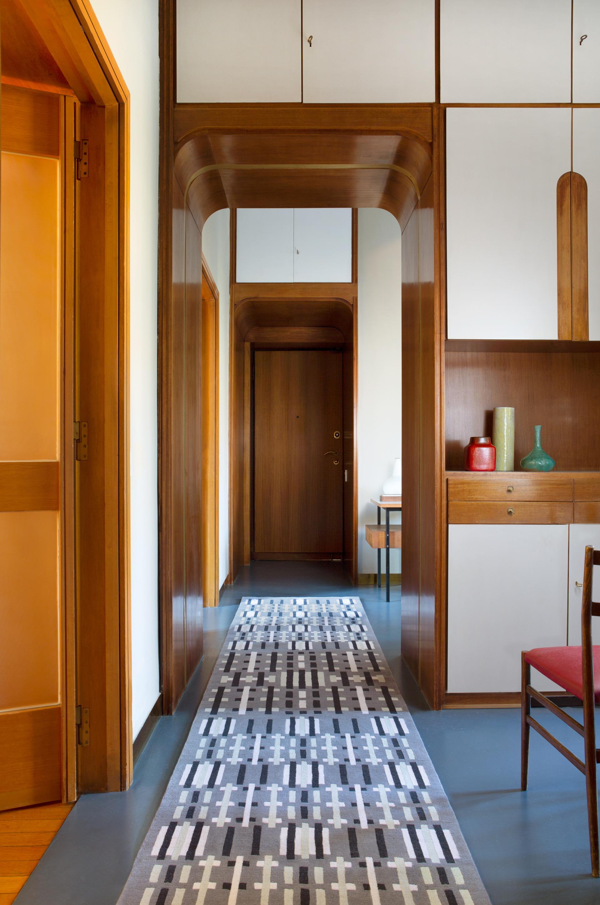 Hallway featuring a colorful rug designed by Jonathan Saunders, showcasing modern design and innovative color interpretation.