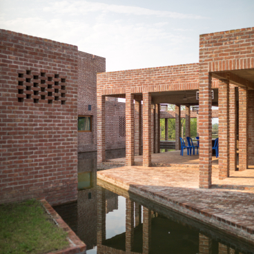Architectural view of the award-winning community hospital in Bangladesh, featuring brick structures and reflective water elements.