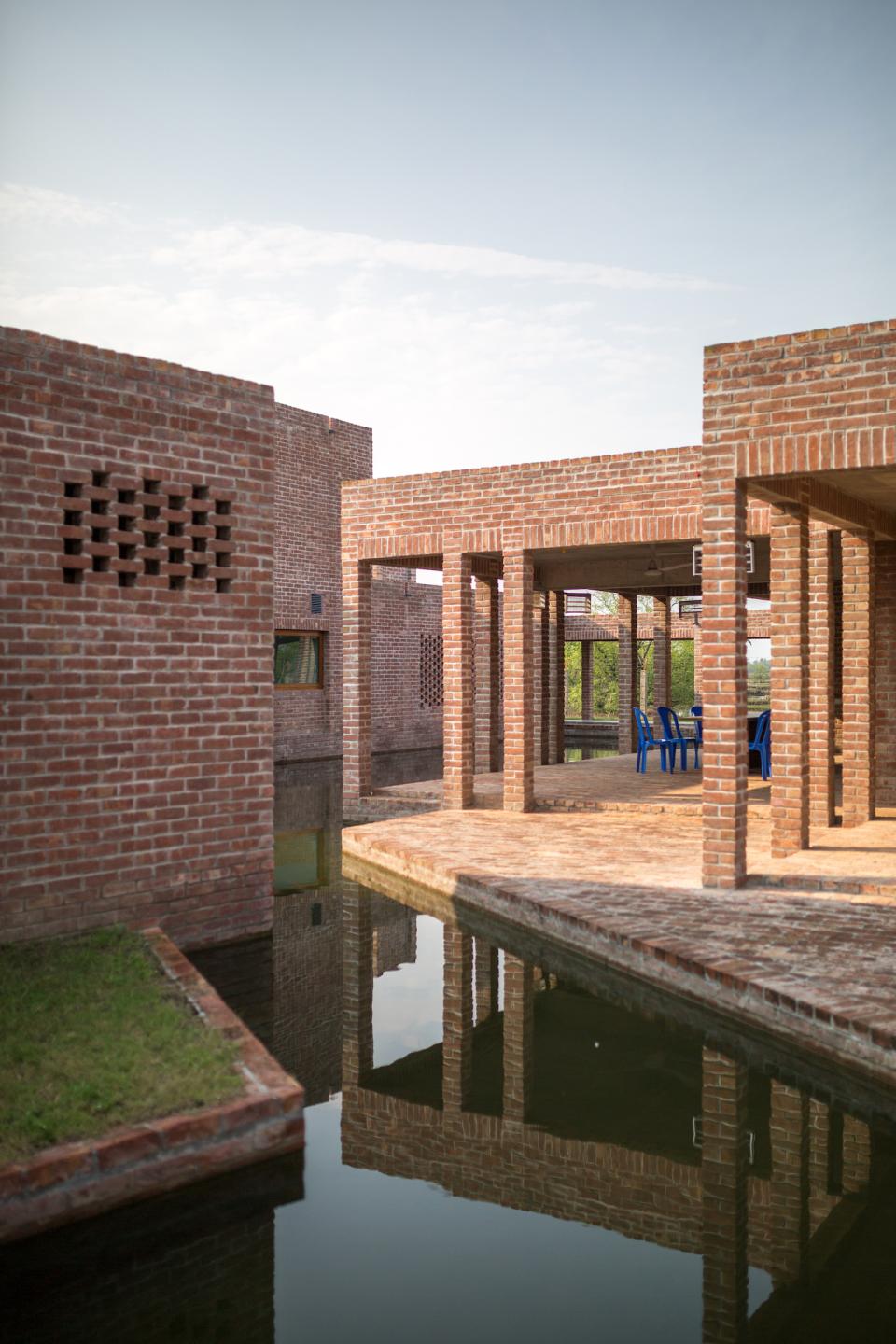 Architectural view of the award-winning community hospital in Bangladesh, featuring brick structures and reflective water elements.