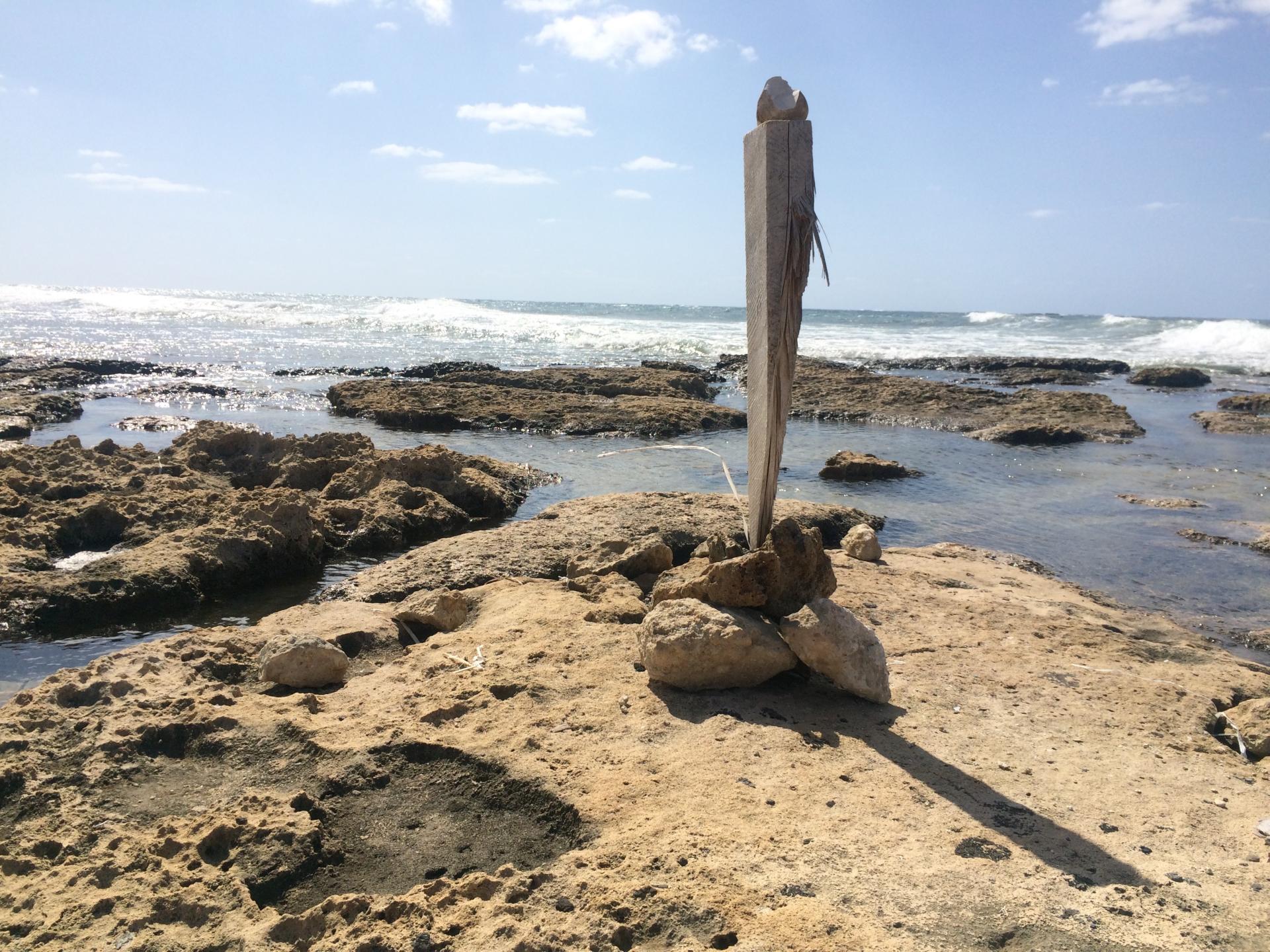 Coastal scene featuring a rock formation and wooden structure, illustrating the impact of climate change on natural environments.
