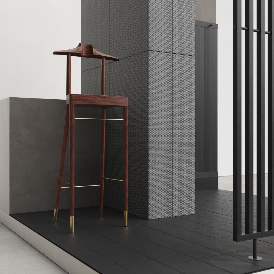 Elegant wooden bar stool in front of intricate tiled wall, showcasing Mutina's collaboration with OEO Studio in interior design.