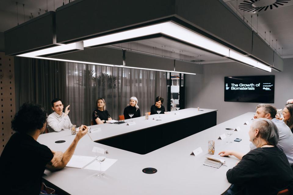 A group discussion on biomaterials takes place around a modern conference table, emphasizing sustainability and innovation.