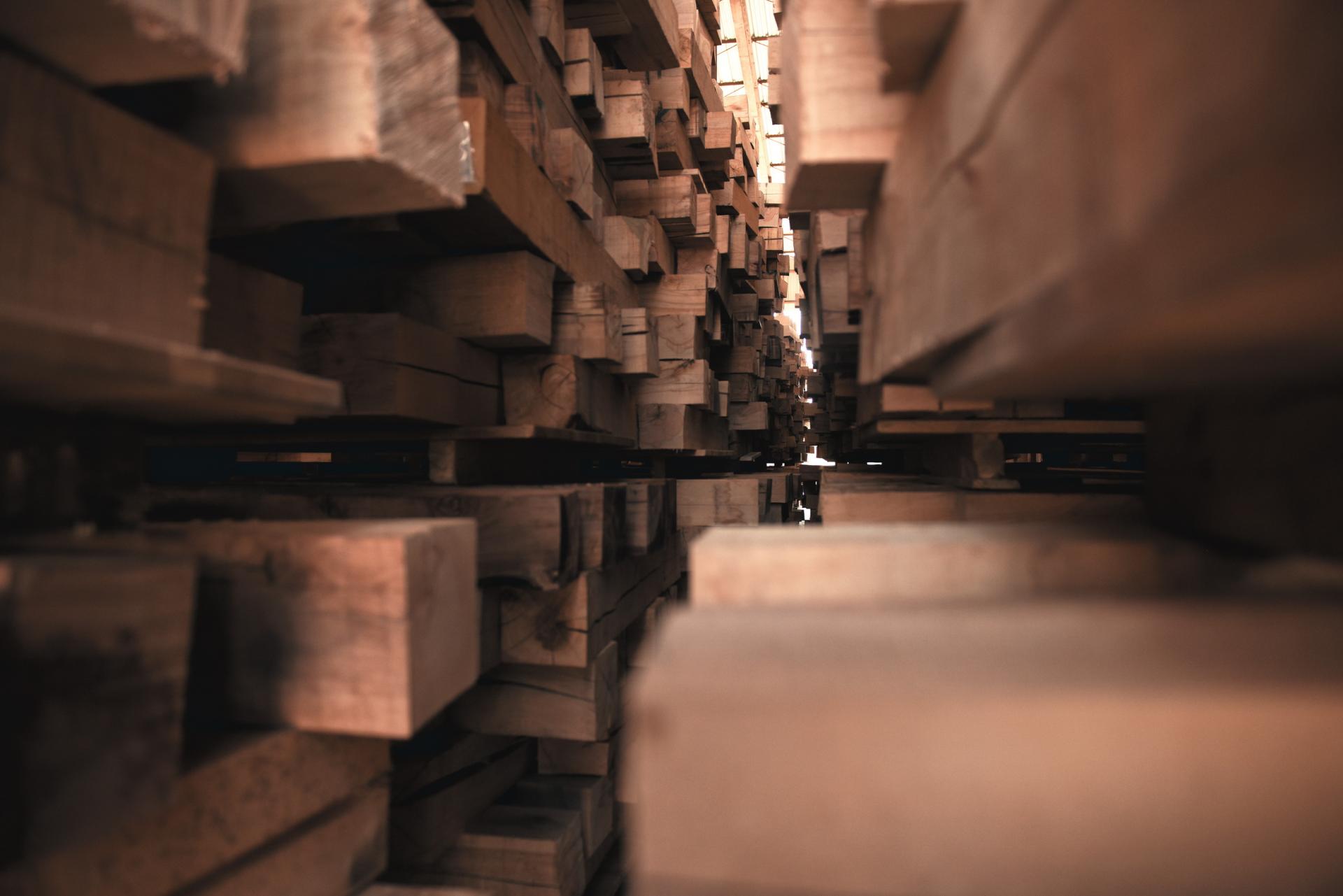 Stacks of sustainably sourced wood in a warehouse, showcasing natural materials and versatile craftsmanship for CRAFTWAND's projects.