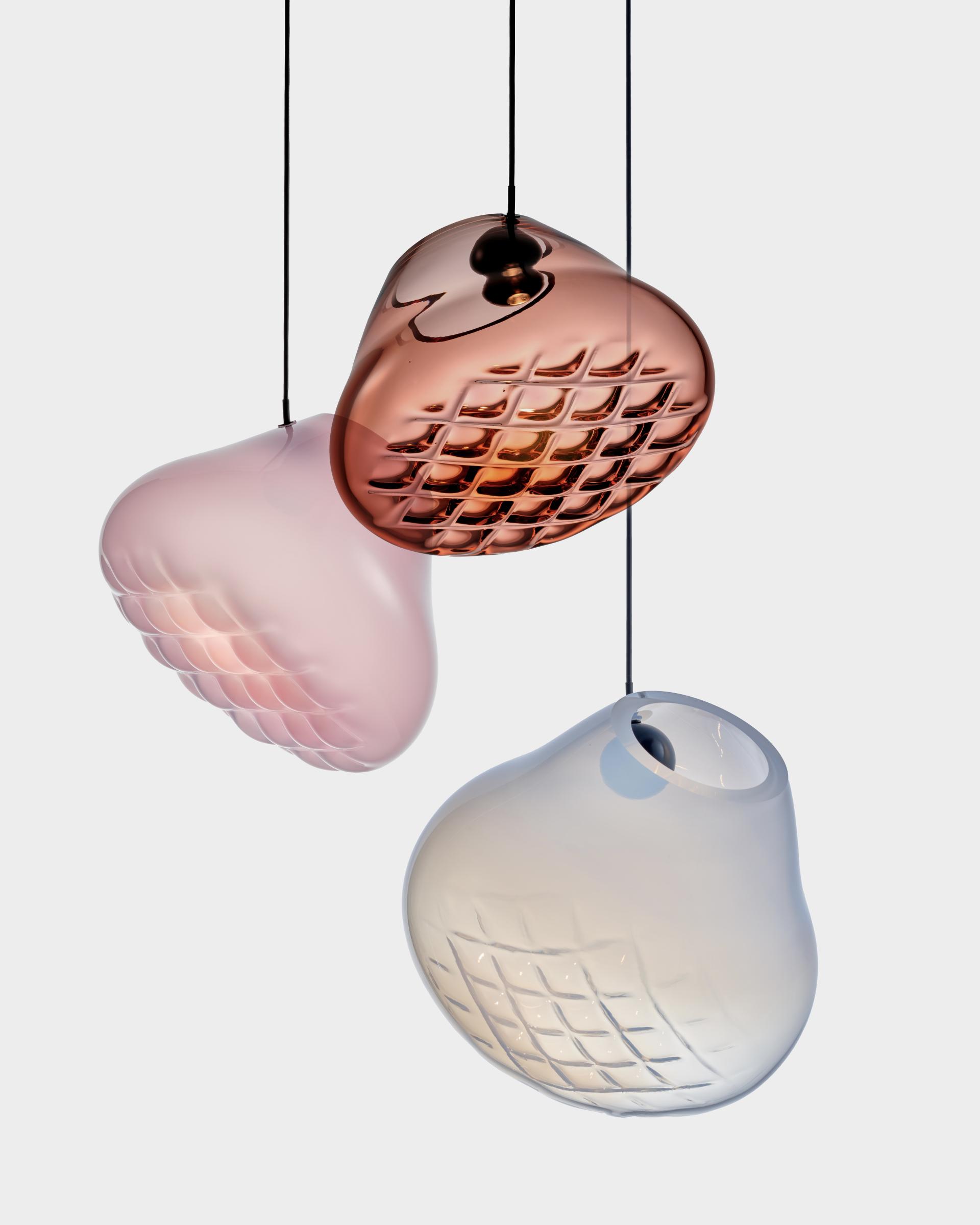 Playful hanging glass light fixtures in soft pink, amber, and clear tones, showcasing modern design and vibrant color palettes.