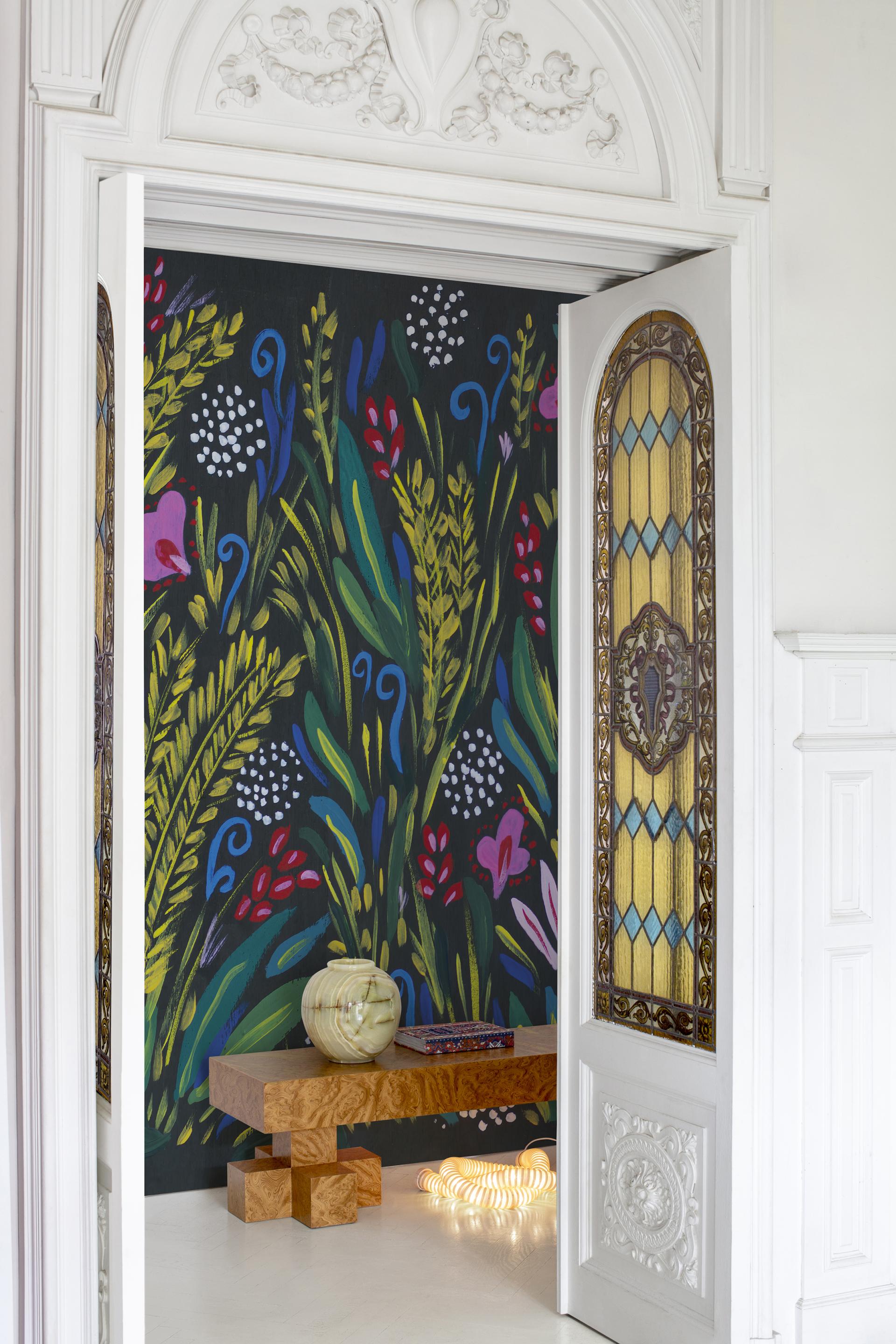 Vibrant floral-patterned wallpaper enhances a contemporary interior with a stylish wooden table and decorative vase.