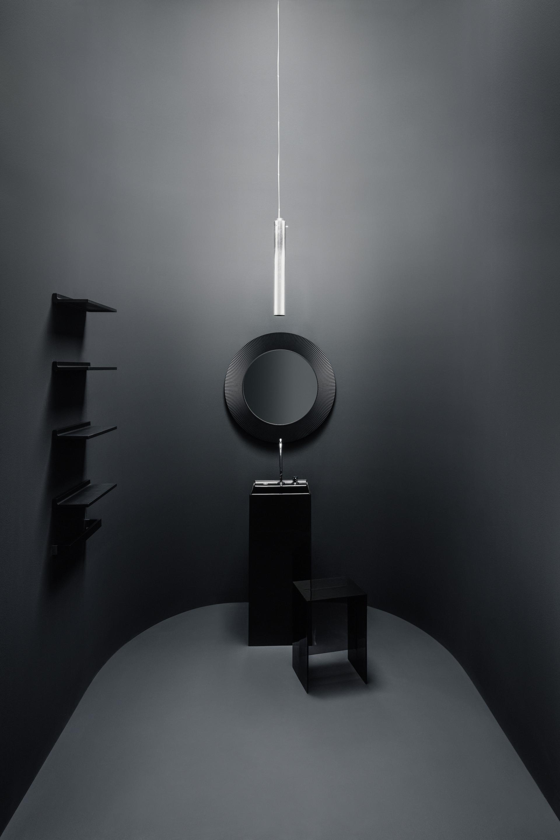 Sleek black bathroom design featuring modern sink, round mirror, and minimalist lighting in a stylish setting.