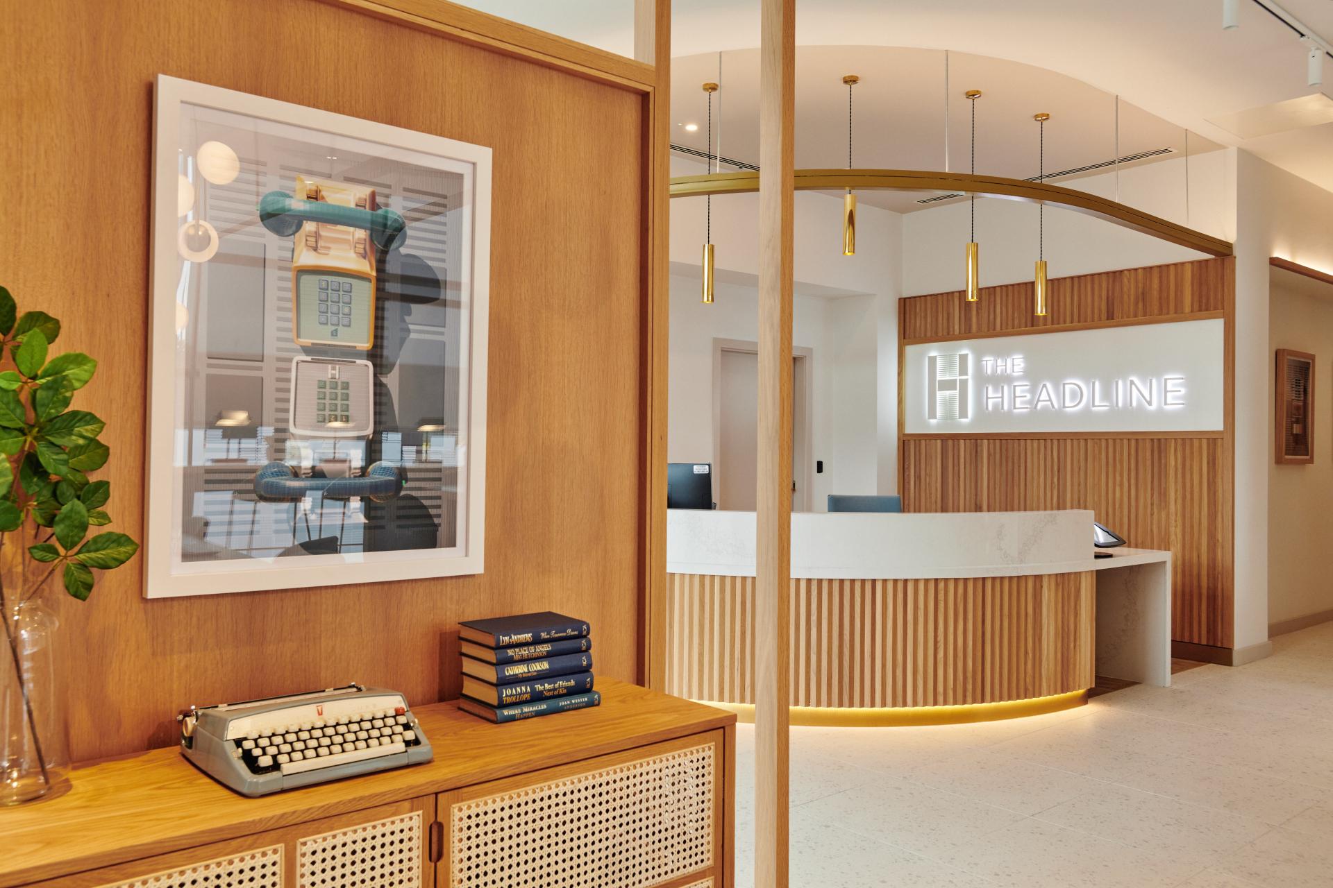 Modern reception area at The Headline, featuring stylish decor, a minimalist front desk, and vintage accessories.