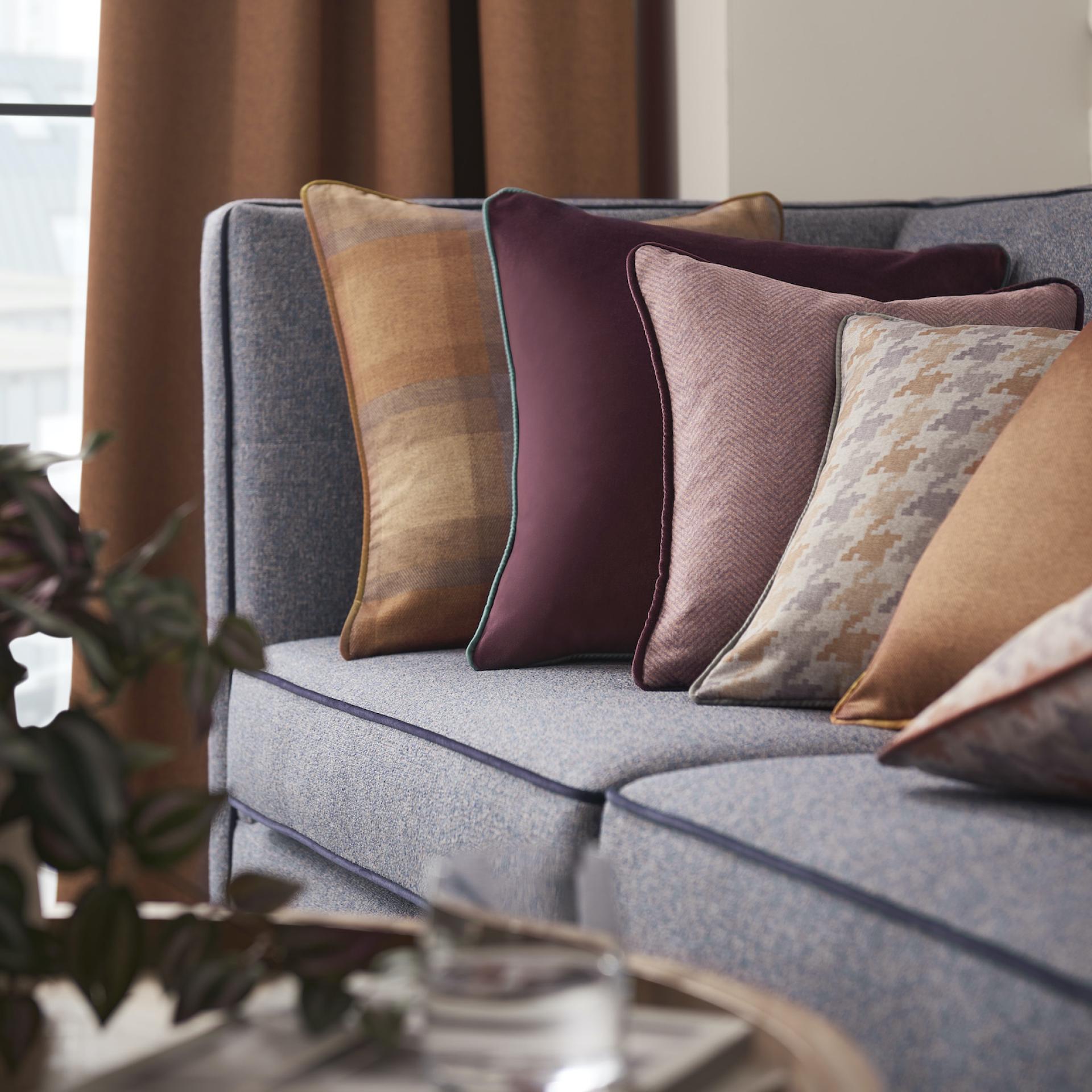 Decorative pillows in rich textures and colors on a stylish blue sofa, enhancing hospitality interior design.