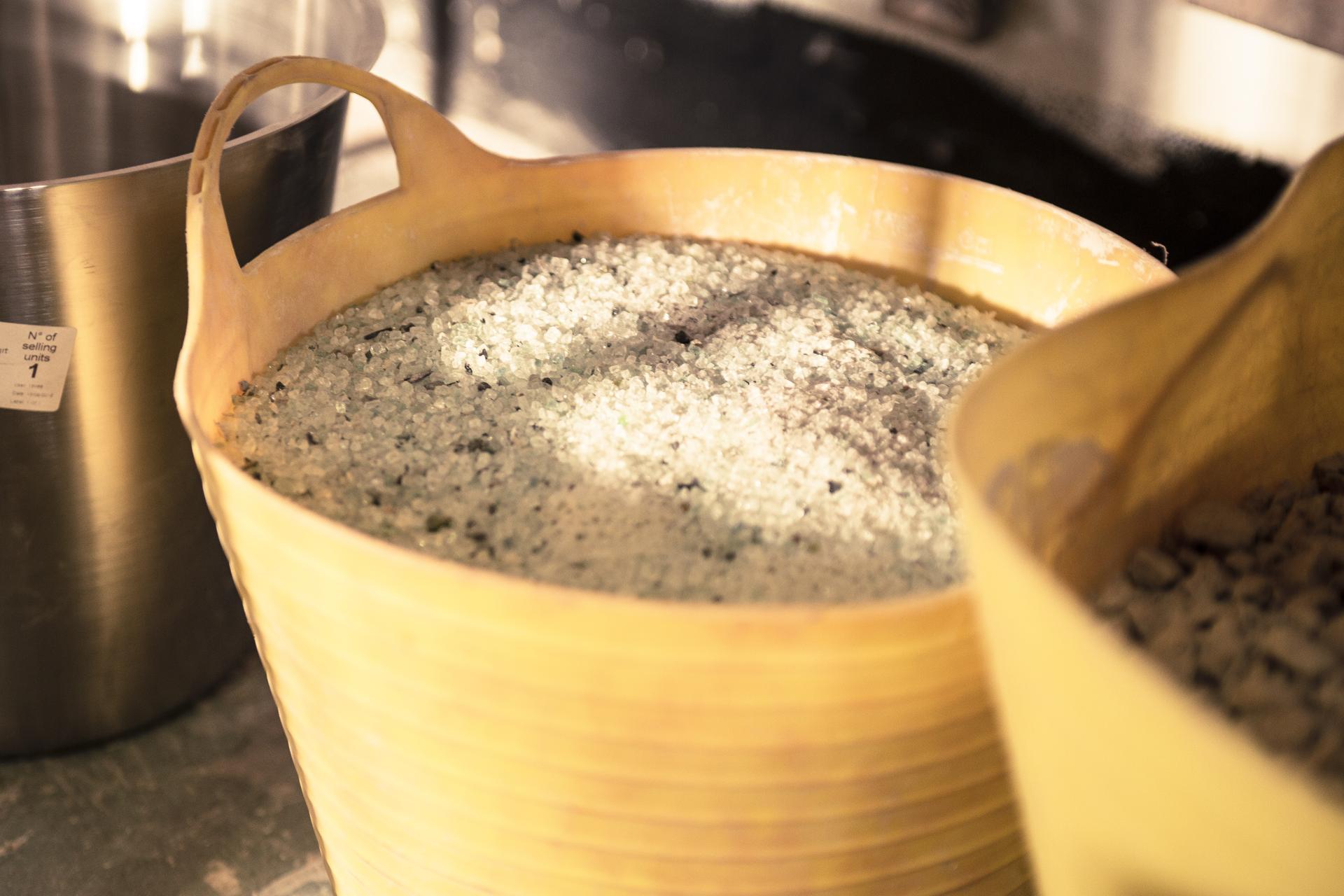 Recycled glass aggregate in a yellow container, highlighting sustainable materials used in innovative surface design.