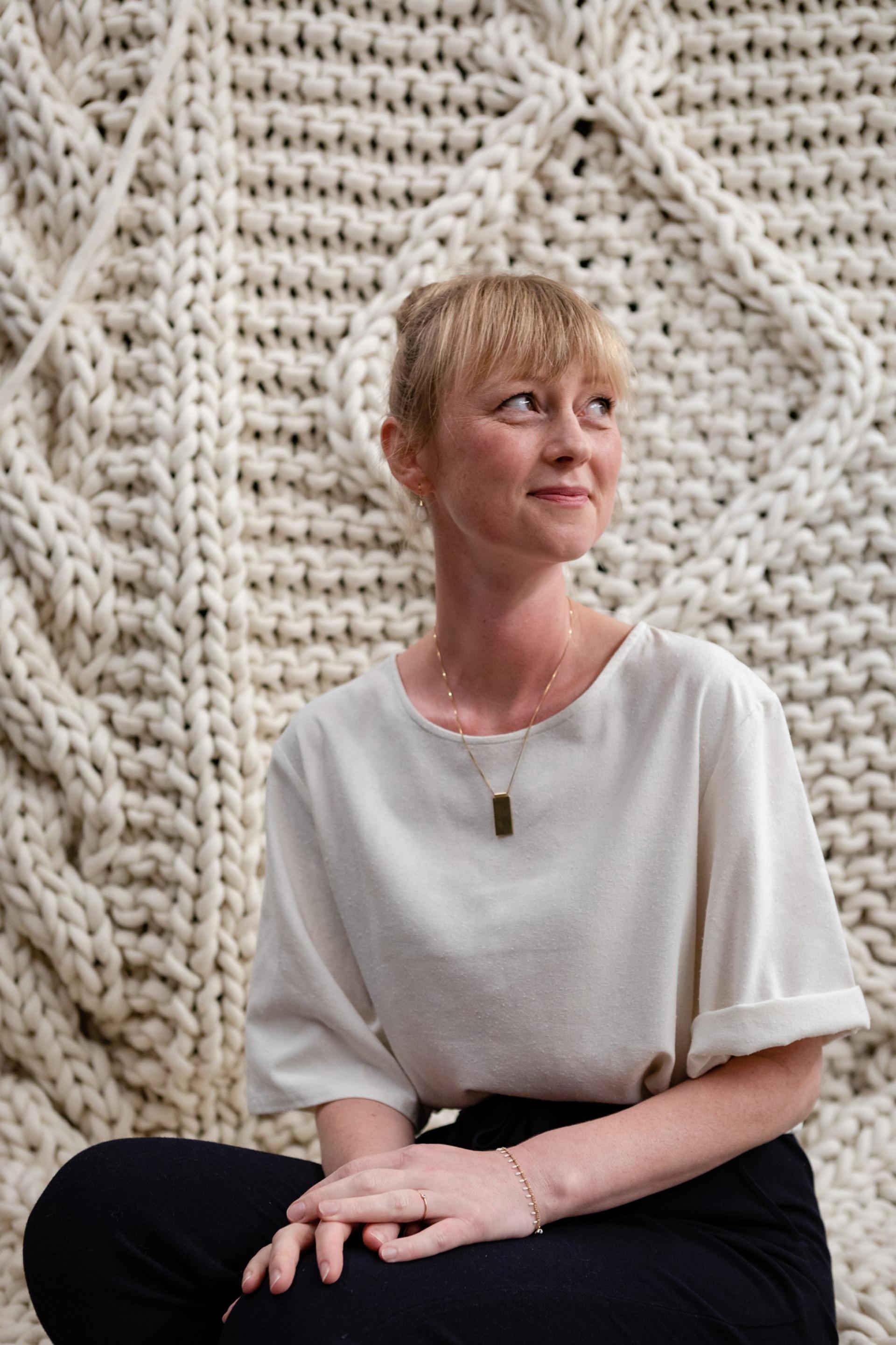 Christien Meindertsma poses in front of a textured, woven wall, exemplifying innovative material design at Vitra Design Museum.