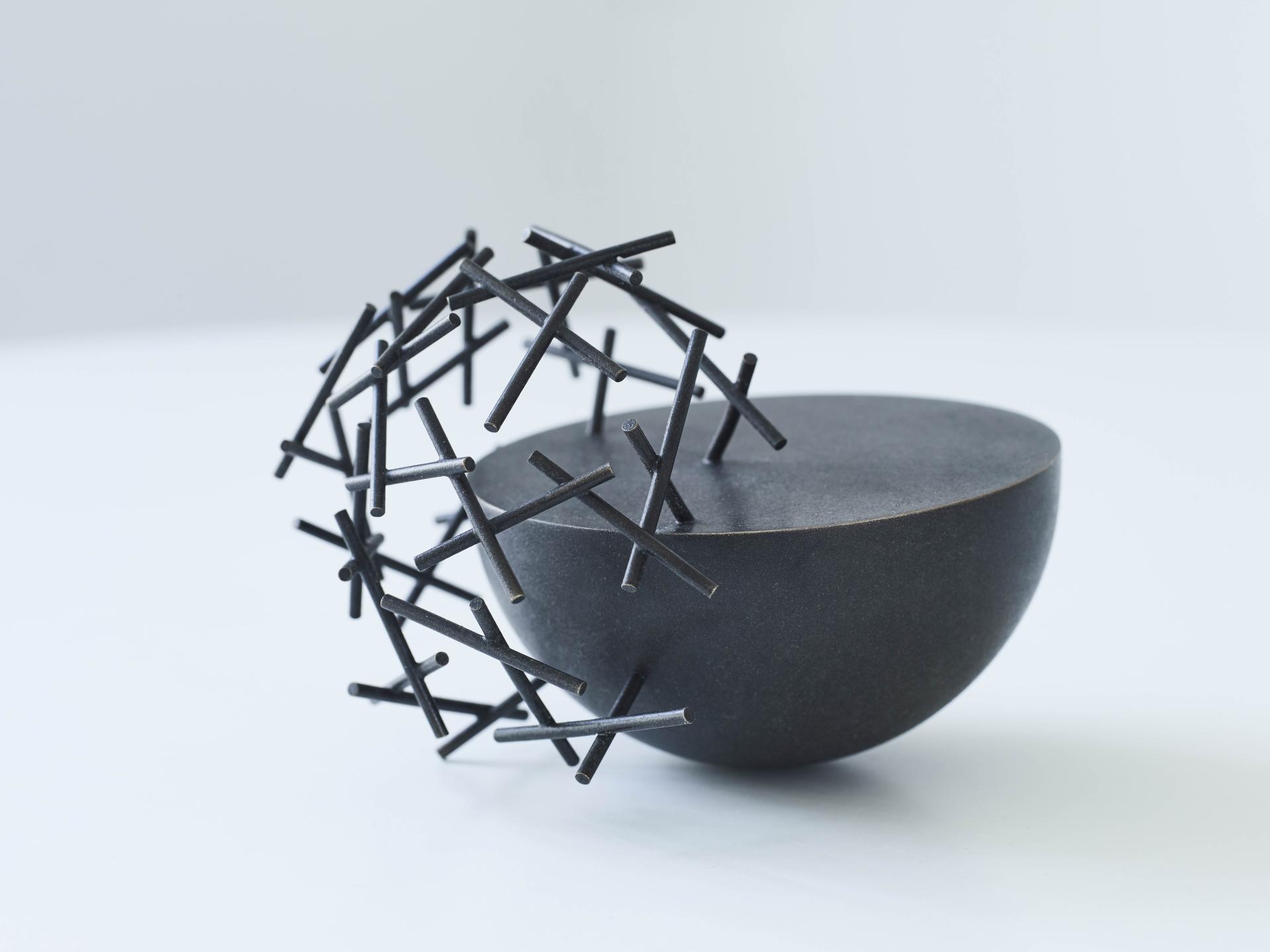 Sculptural black vessel with intricate, intersecting metal rods, featured in London Craft Week 2019 event.