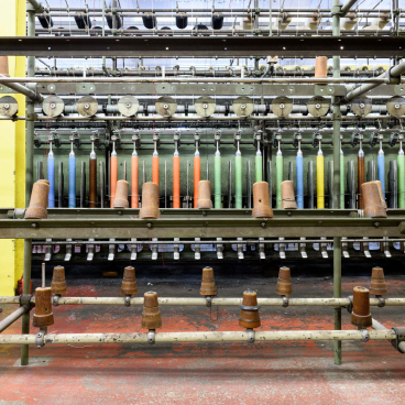 Textile production machinery with colorful threads, highlighting Kvadrat's innovative upholstery fabric manufacturing process in Denmark.