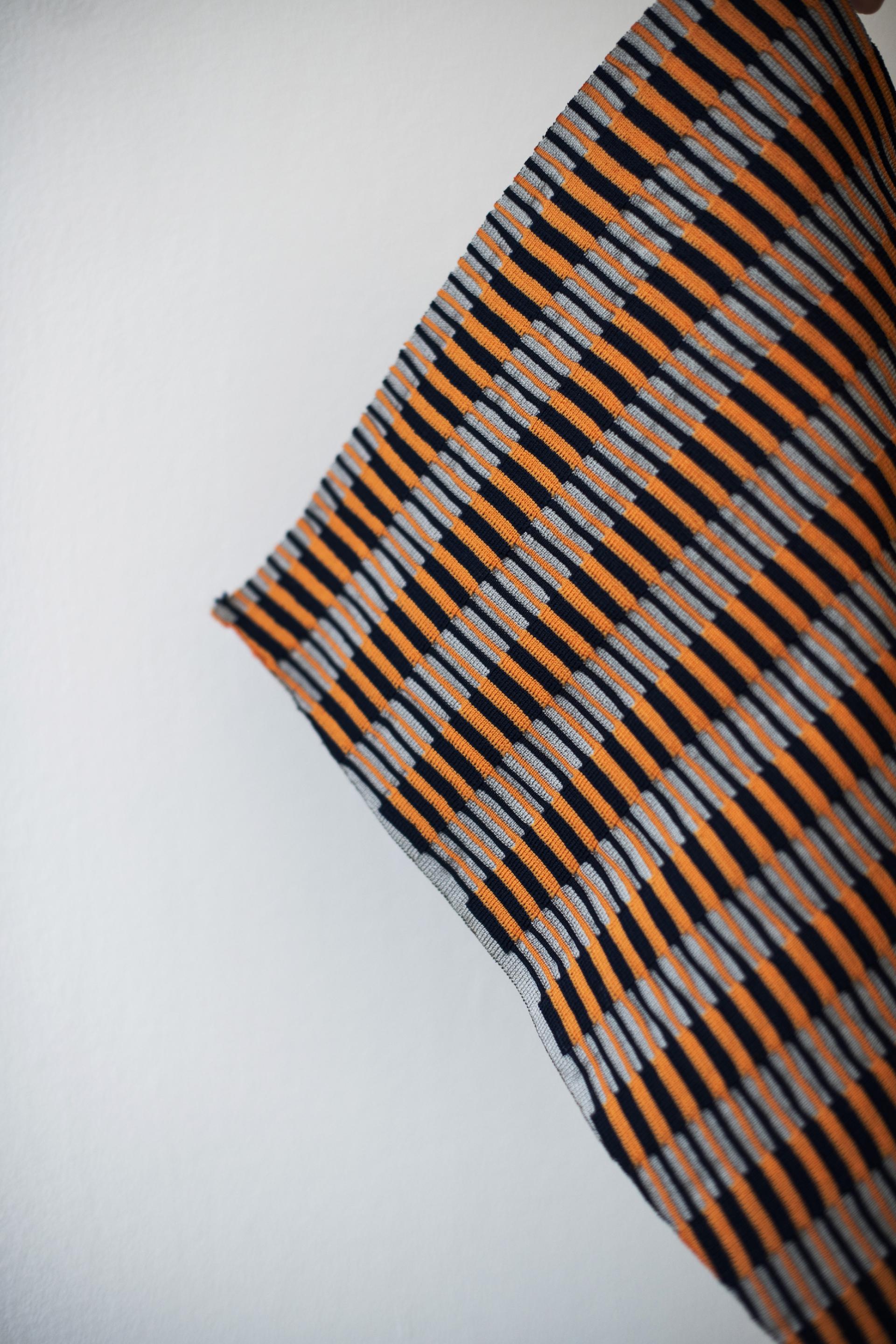 Textile design featuring a bold striped pattern in orange, gray, and black, highlighting innovative surface design trends.