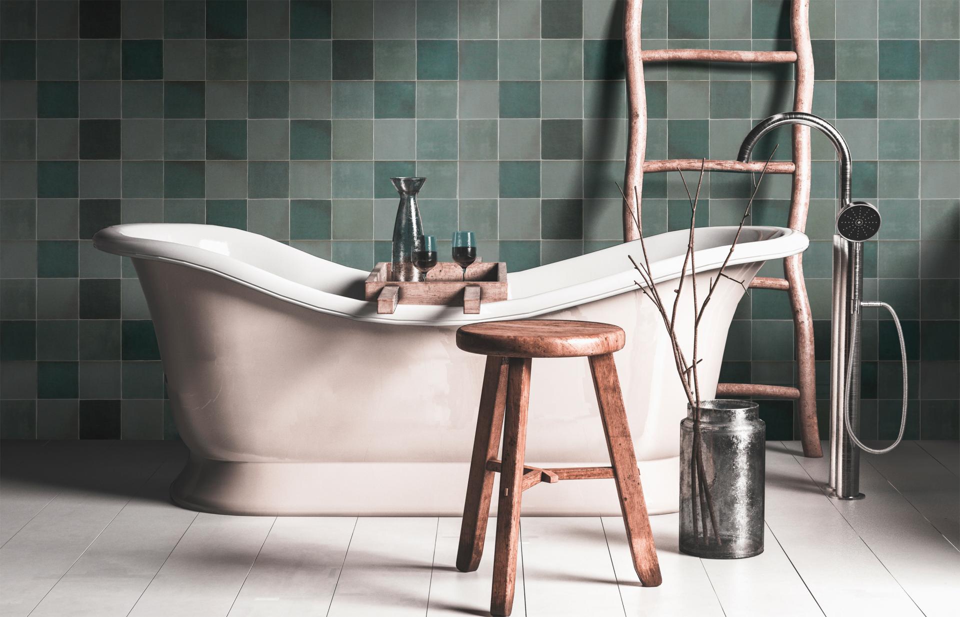Stylish bathroom featuring a freestanding tub, wooden stool, and green tiled walls, showcasing 2019 tile trends.