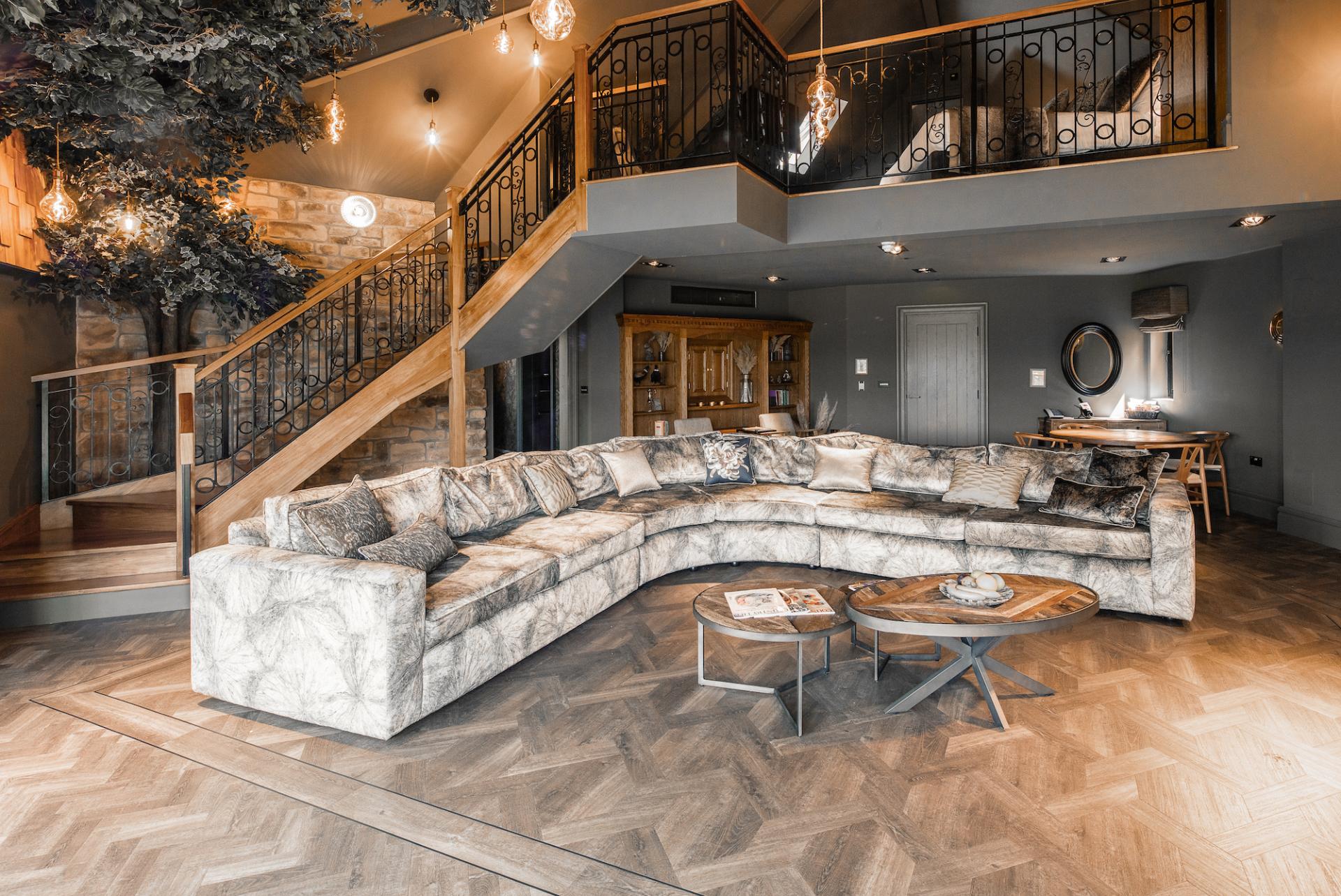 Luxury interior of the Dove Treehouse at Ramside Hall Hotel, featuring a stylish curved sofa and wooden staircase.