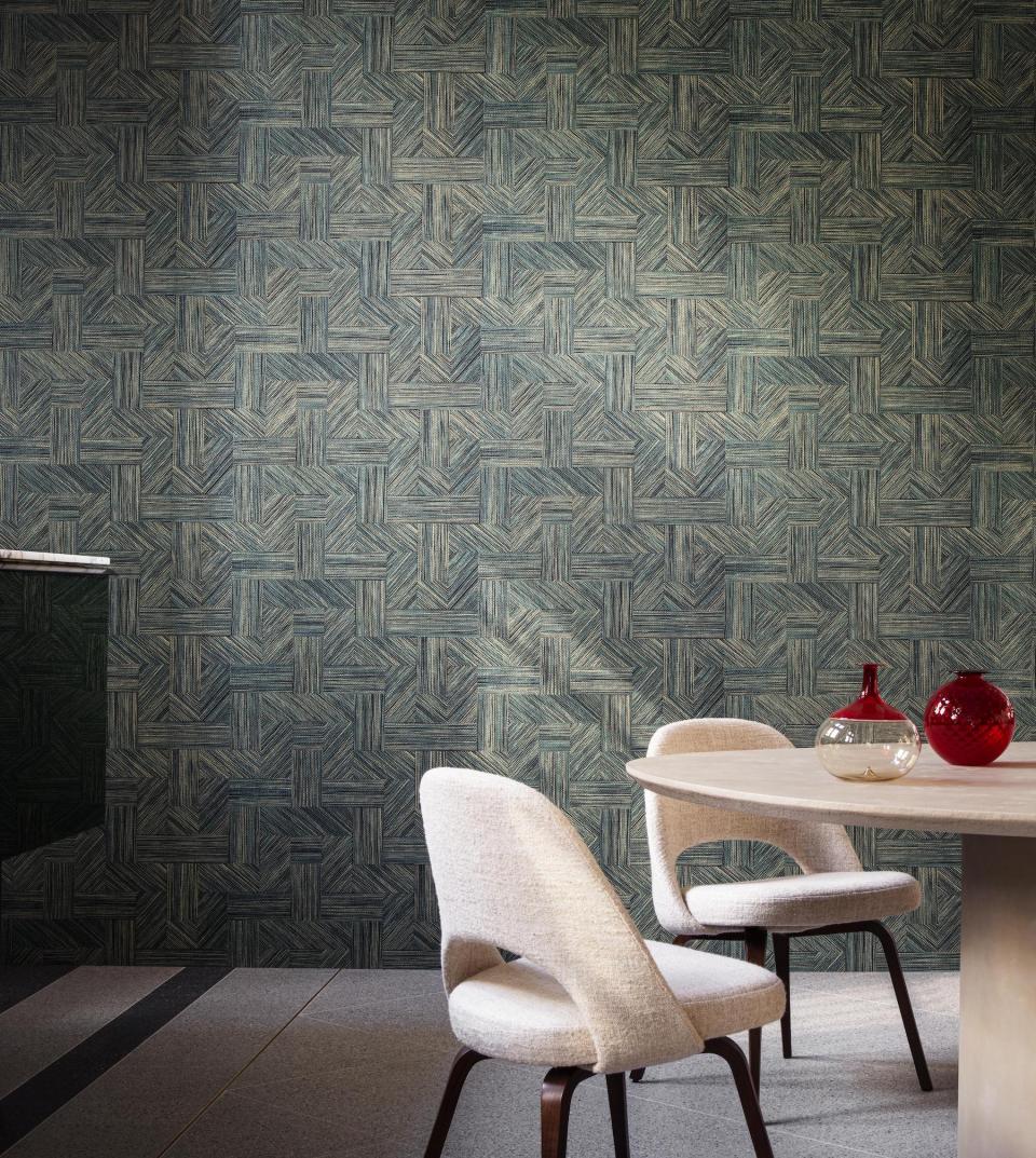 Tangram-inspired patterned wallpaper complements modern dining area with stylish round table and elegant chairs.