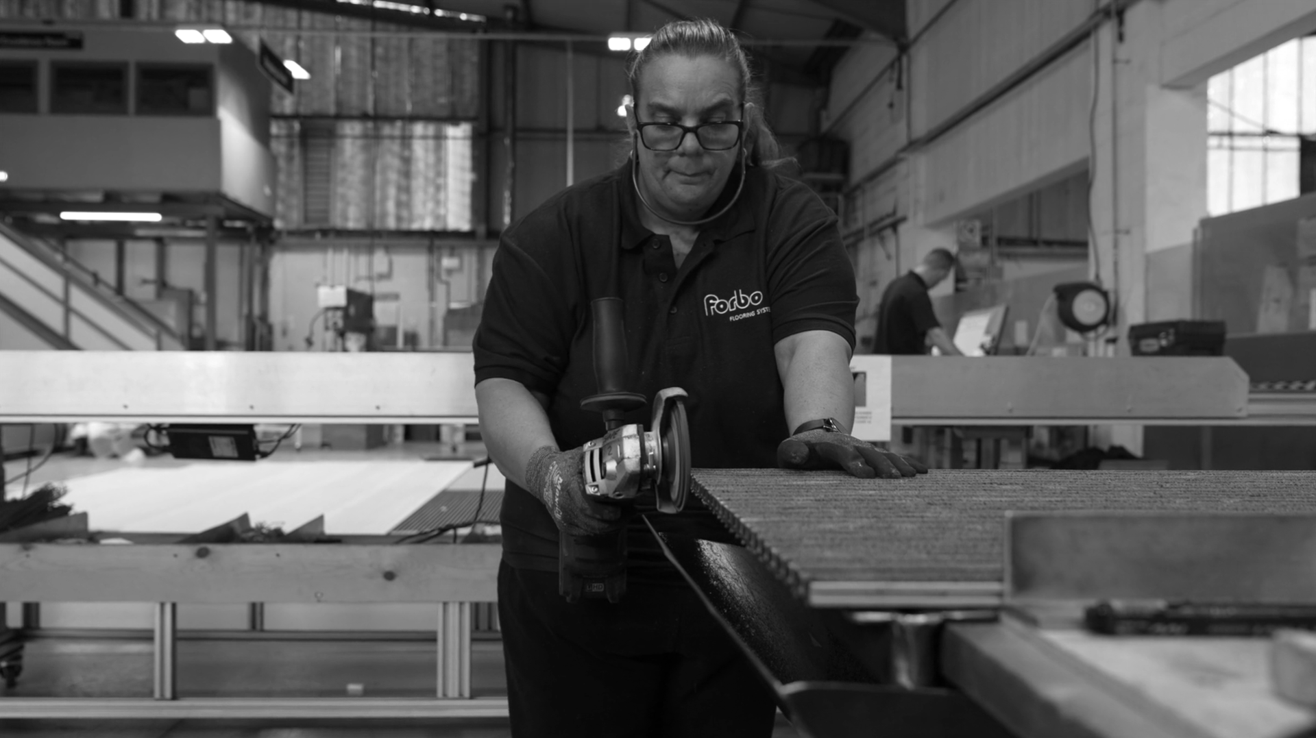 Worker at Forbo Flooring Systems using a tool on a production line, highlighting craftsmanship in sustainable flooring manufacturing.