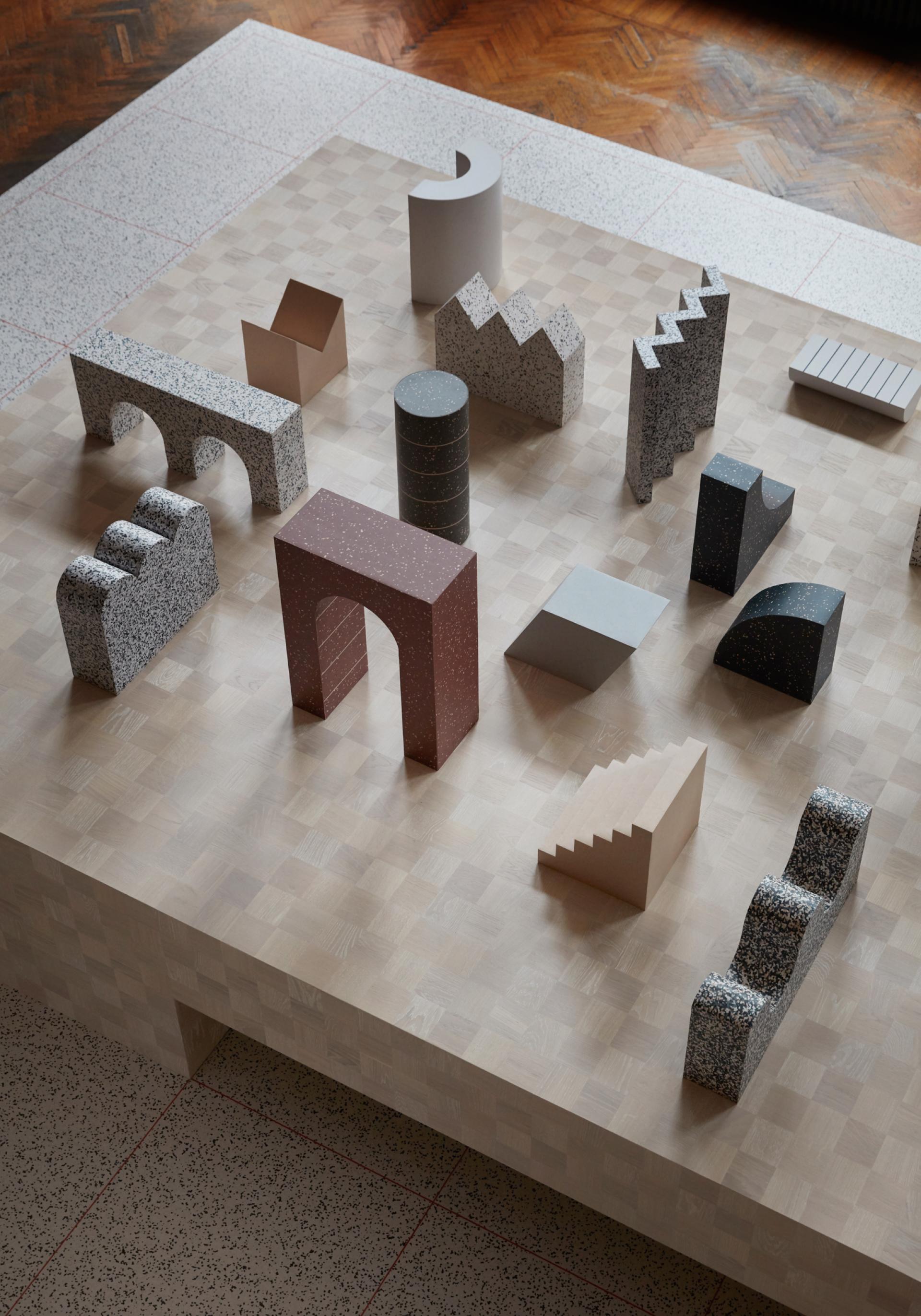 Abstract geometric shapes made of modern materials, displayed on a textured surface, showcasing creativity at Milan Design Week by Tarkett.