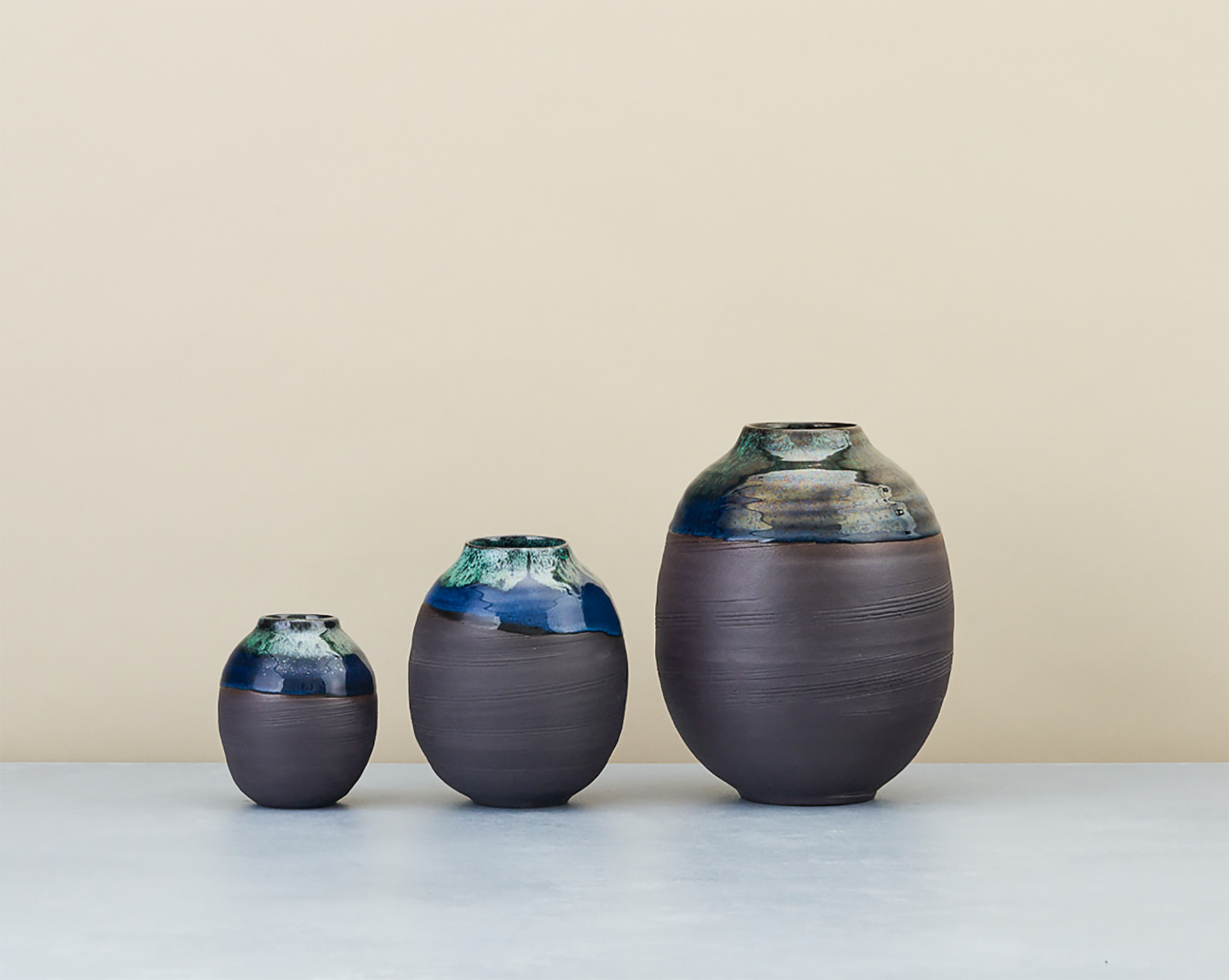 Elegant ceramic vases in varying sizes, showcasing unique glazing and craftsmanship, representing Design Nation's emphasis on design and craft.