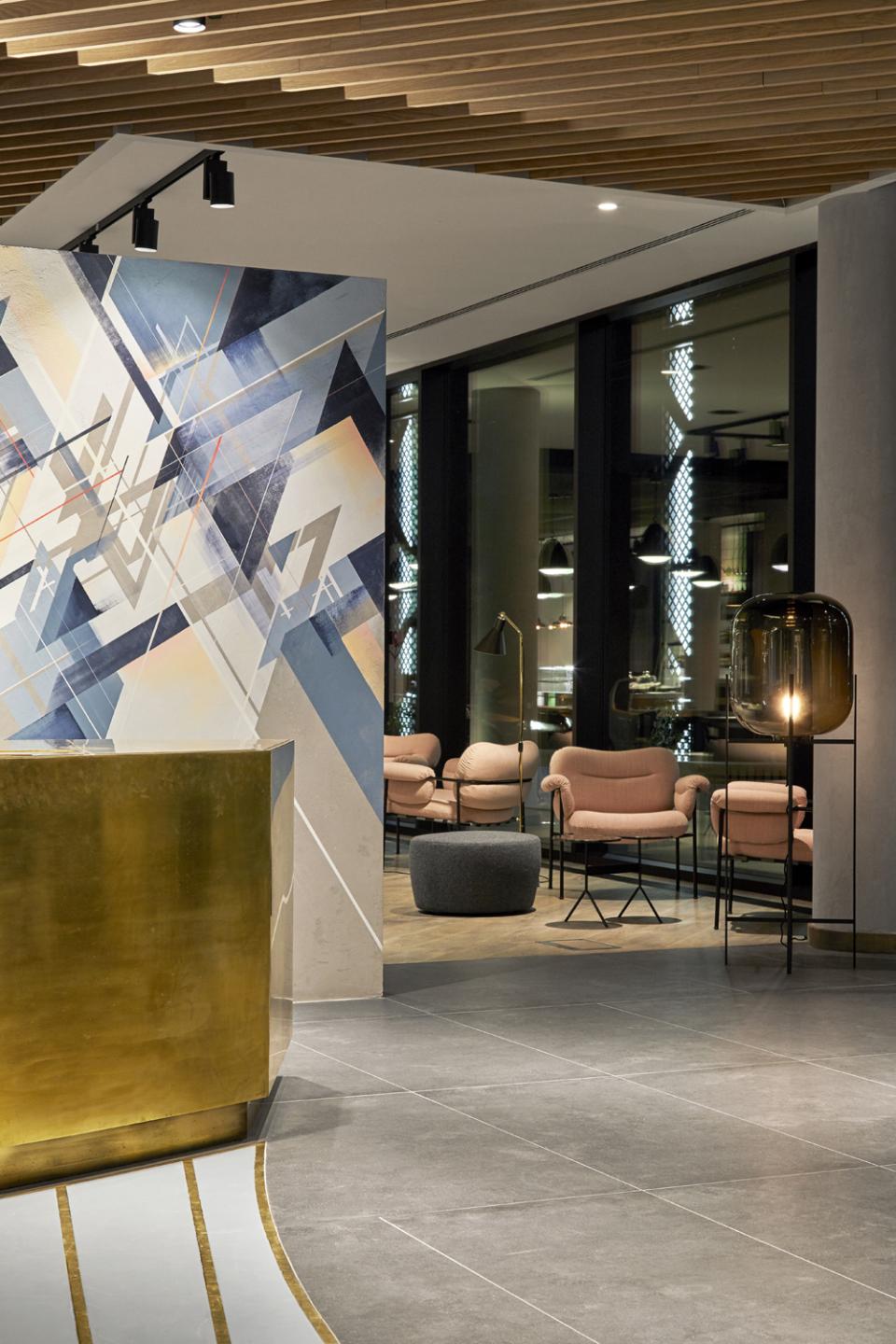 Modern lobby design for PURO Kraków Kazimierz featuring artistic mural, golden reception desk, and stylish seating area.