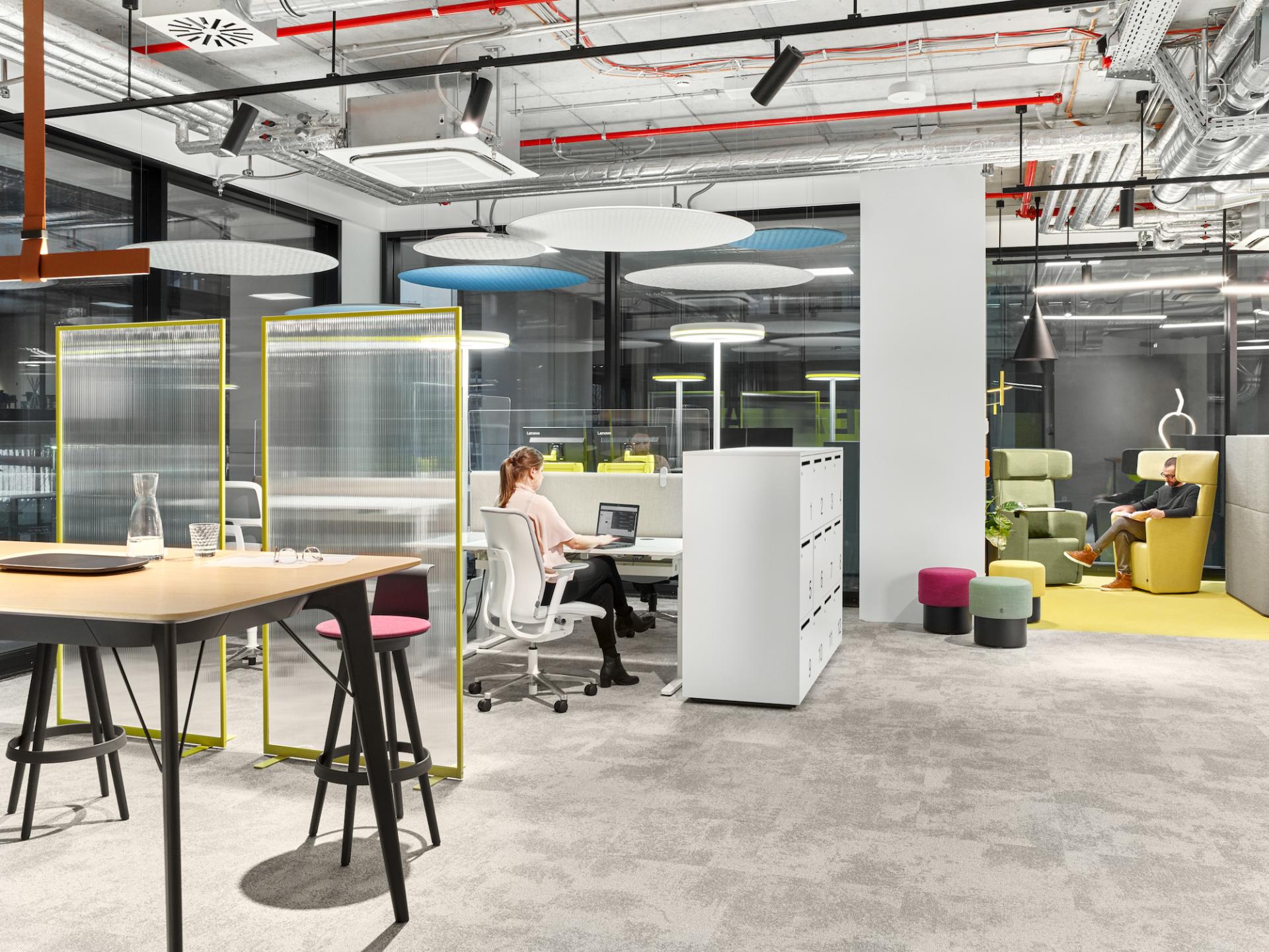 Modern office space designed for collaboration and productivity, featuring flexible seating and transparent dividers for safety.