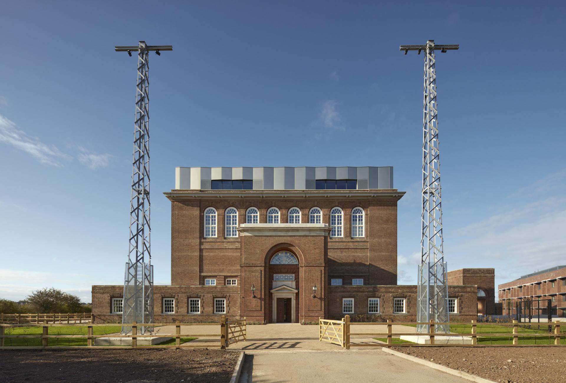 Historic brick building with modern rooftop and adjacent towers, showcasing innovative retrofitting in sustainable architecture.