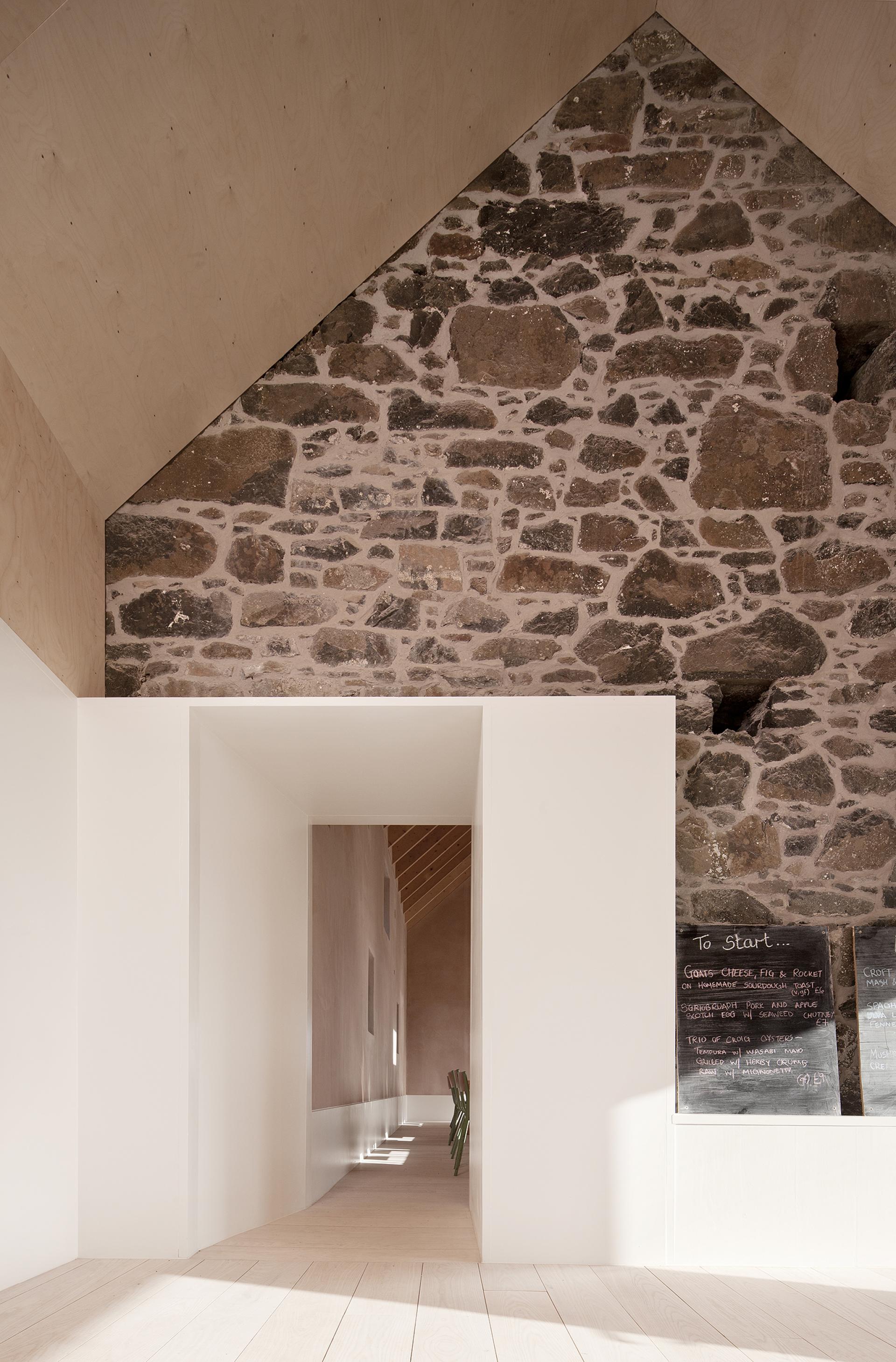Interior of Croft3, featuring restored stone walls, modern design elements, and natural light illuminating the hallway.