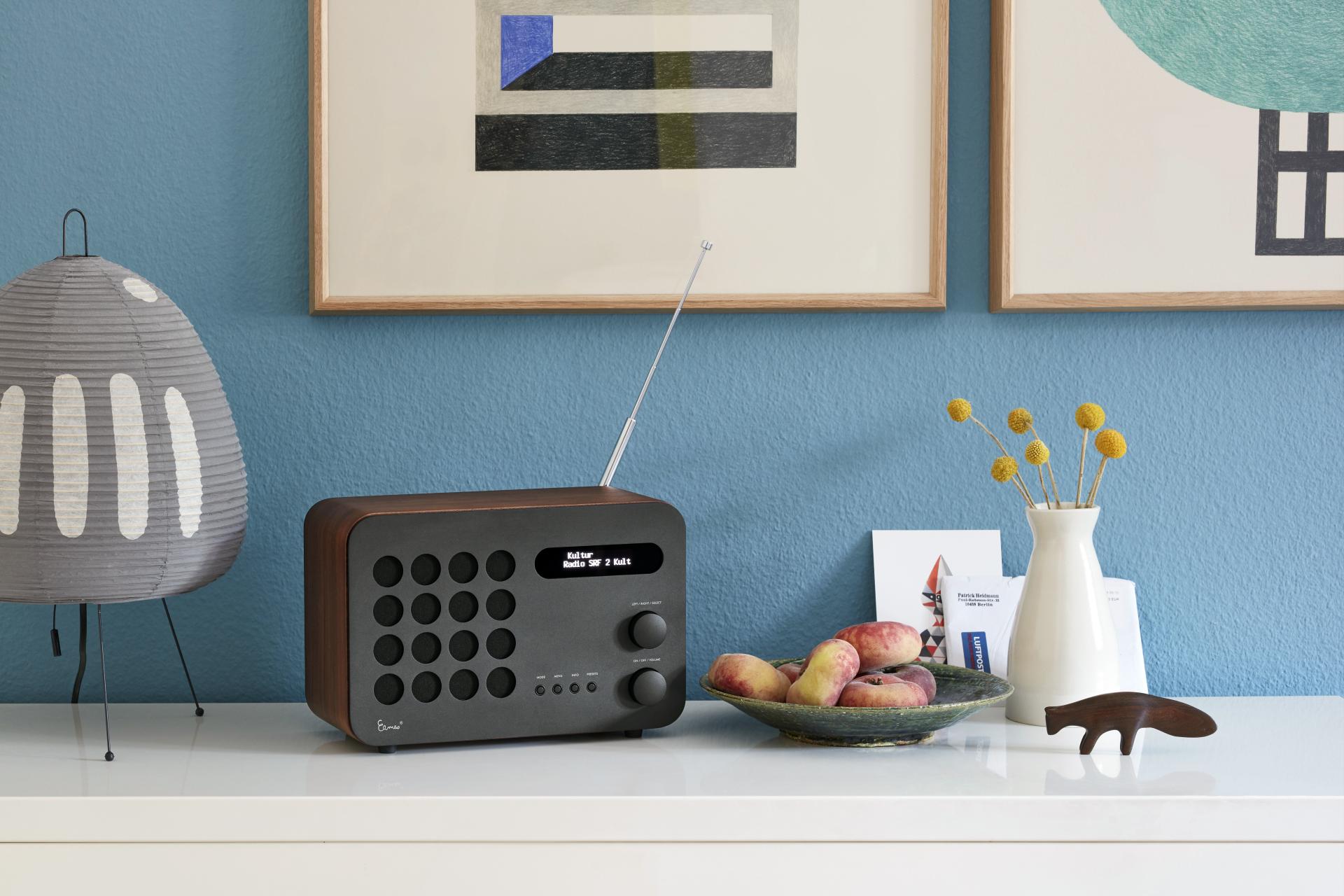 Modern Vitra accessories displayed on a table, featuring a radio, decorative vase, fruit bowl, and art.