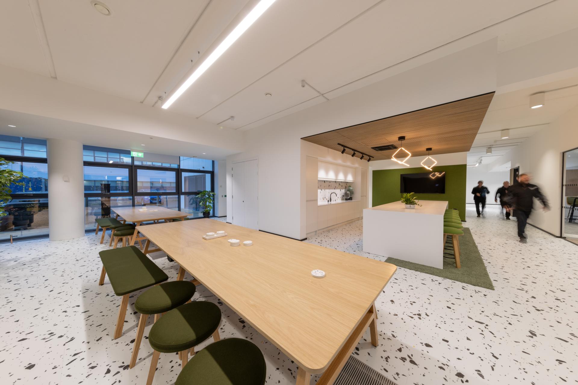 Modern office interior featuring bold terrazzo flooring, biophilic design elements, and collaborative meeting spaces.