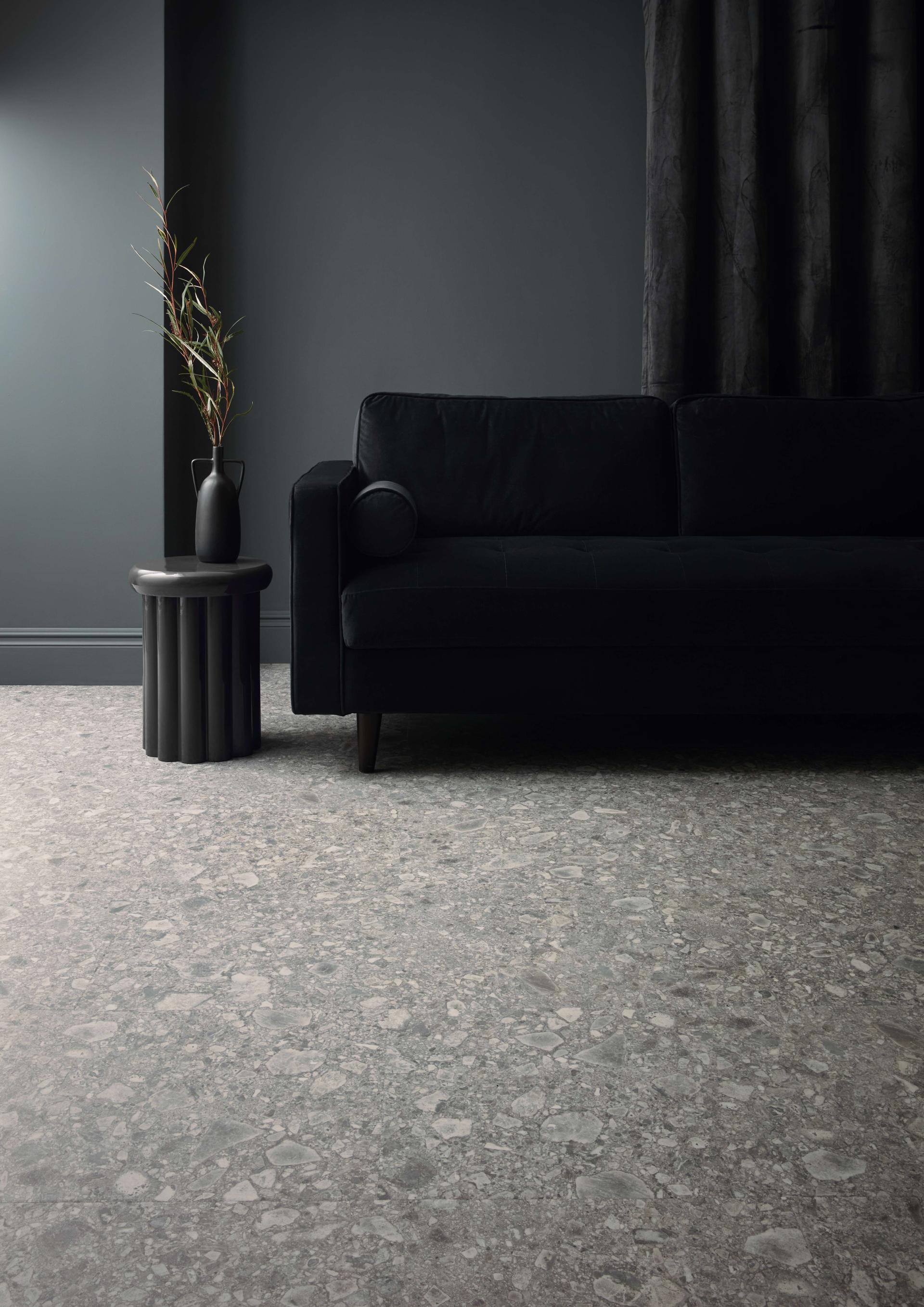 Stylish living room featuring Karndean's elegant stone flooring, a black sofa, and modern decor elements.