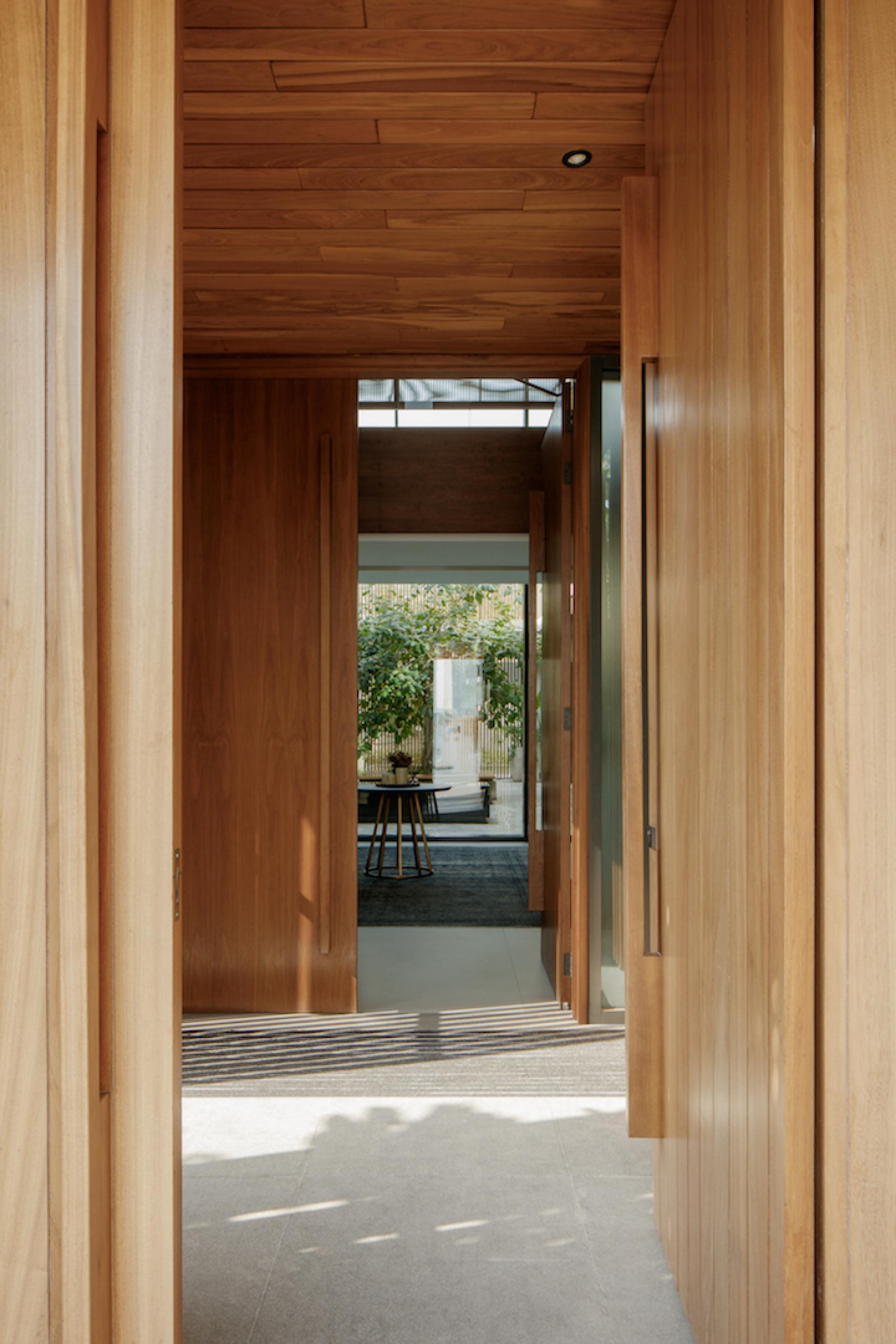 Elegant wooden hallway leading to a serene living space with natural light and greenery at Villa Jumeirah.