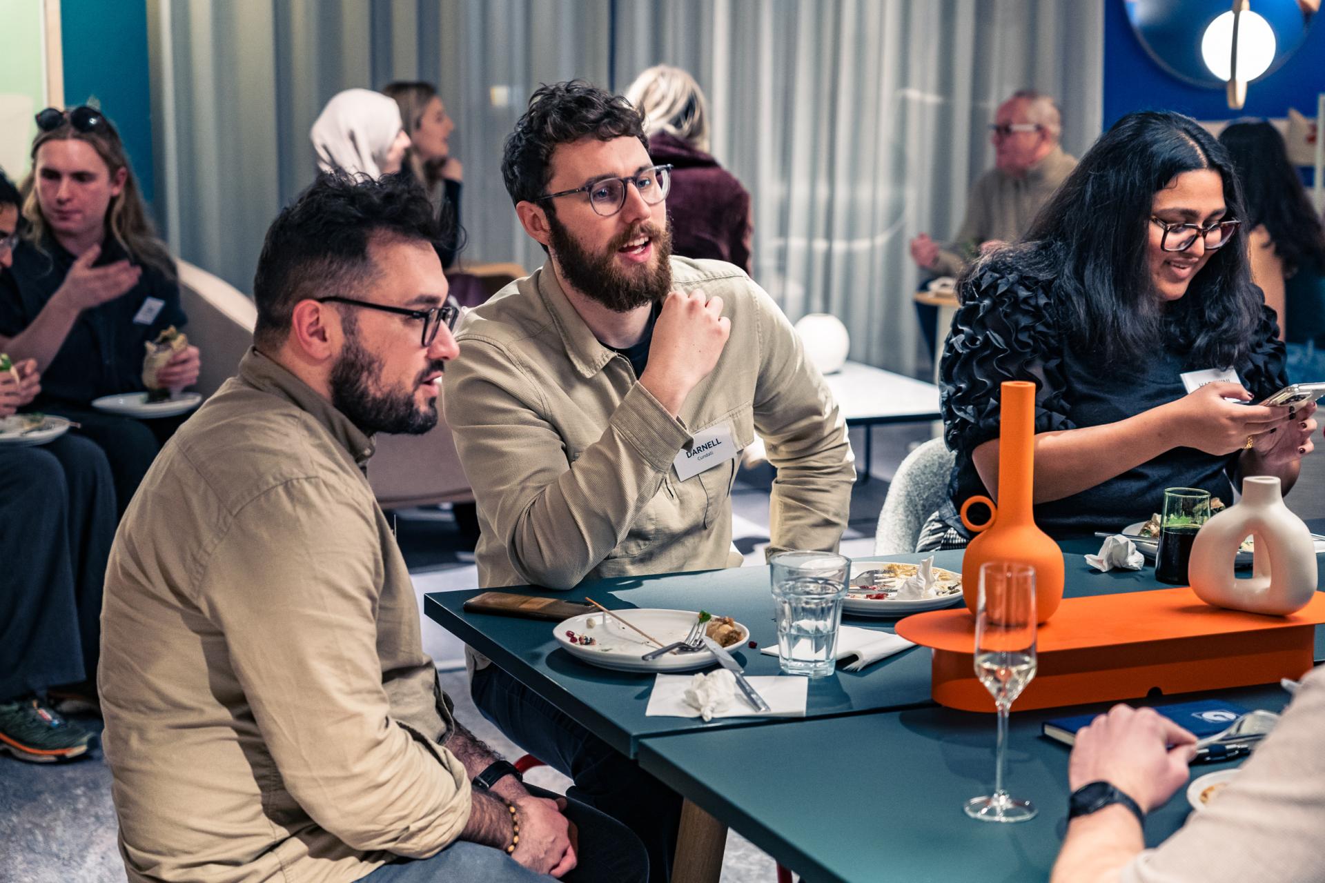 Engaged group discussing climate action at a networking event, surrounded by drinks and sustainable food options.