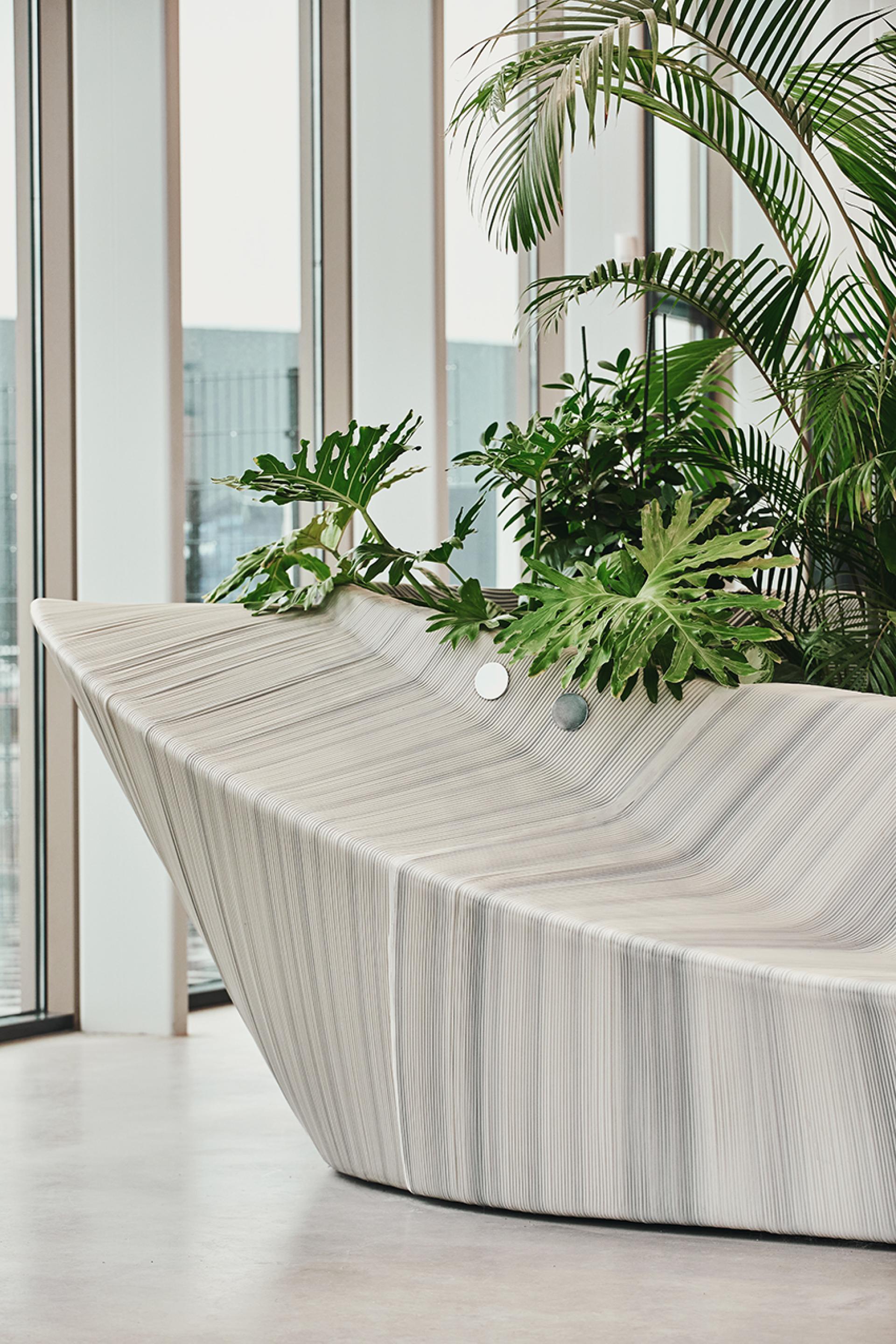 Multifunctional entrance furniture by The New Raw, featuring a sculptural design complemented by lush indoor plants.