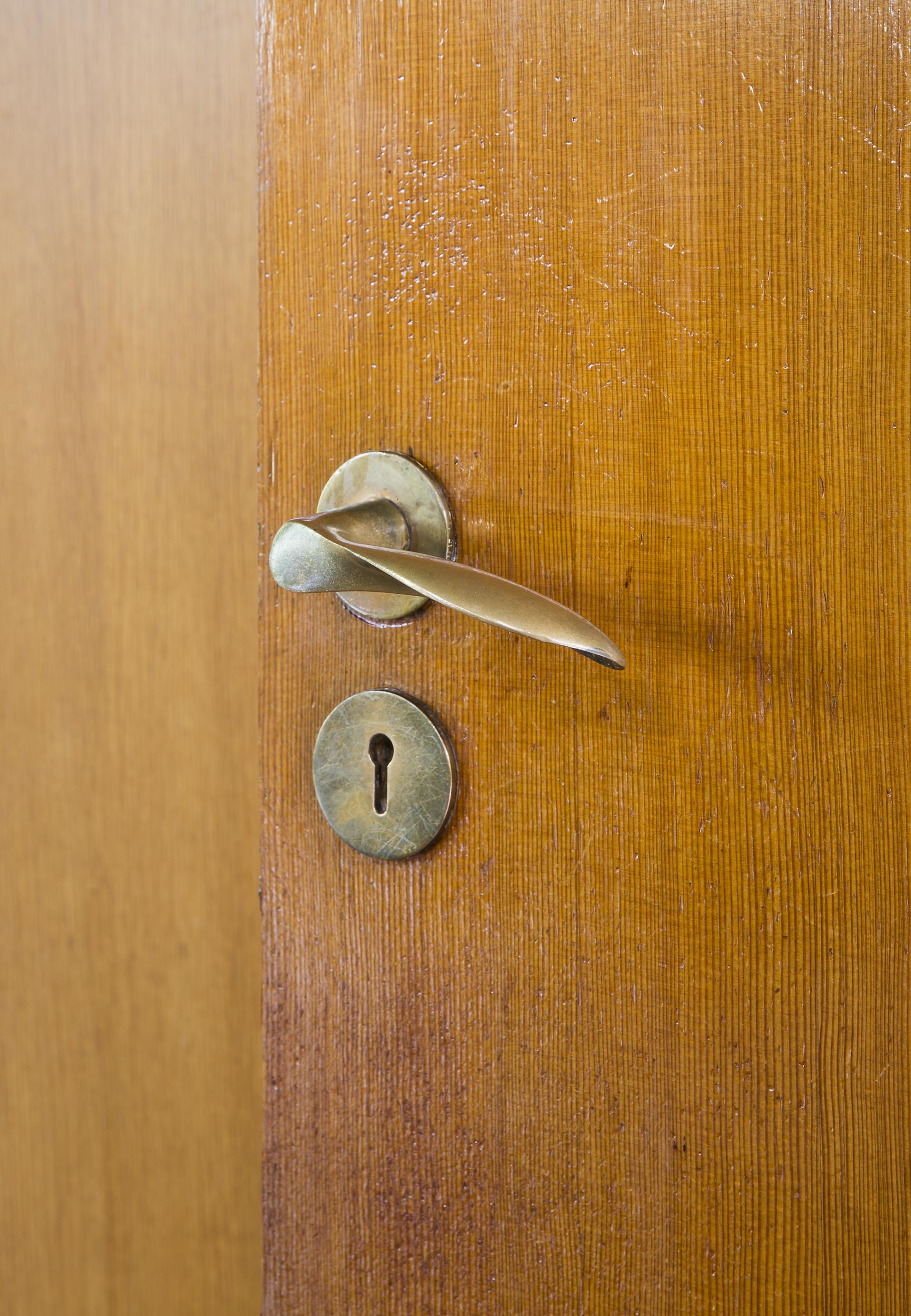 Brass door handle and keyhole on wooden door, reflecting the architectural design of St Catherine’s College, Oxford.