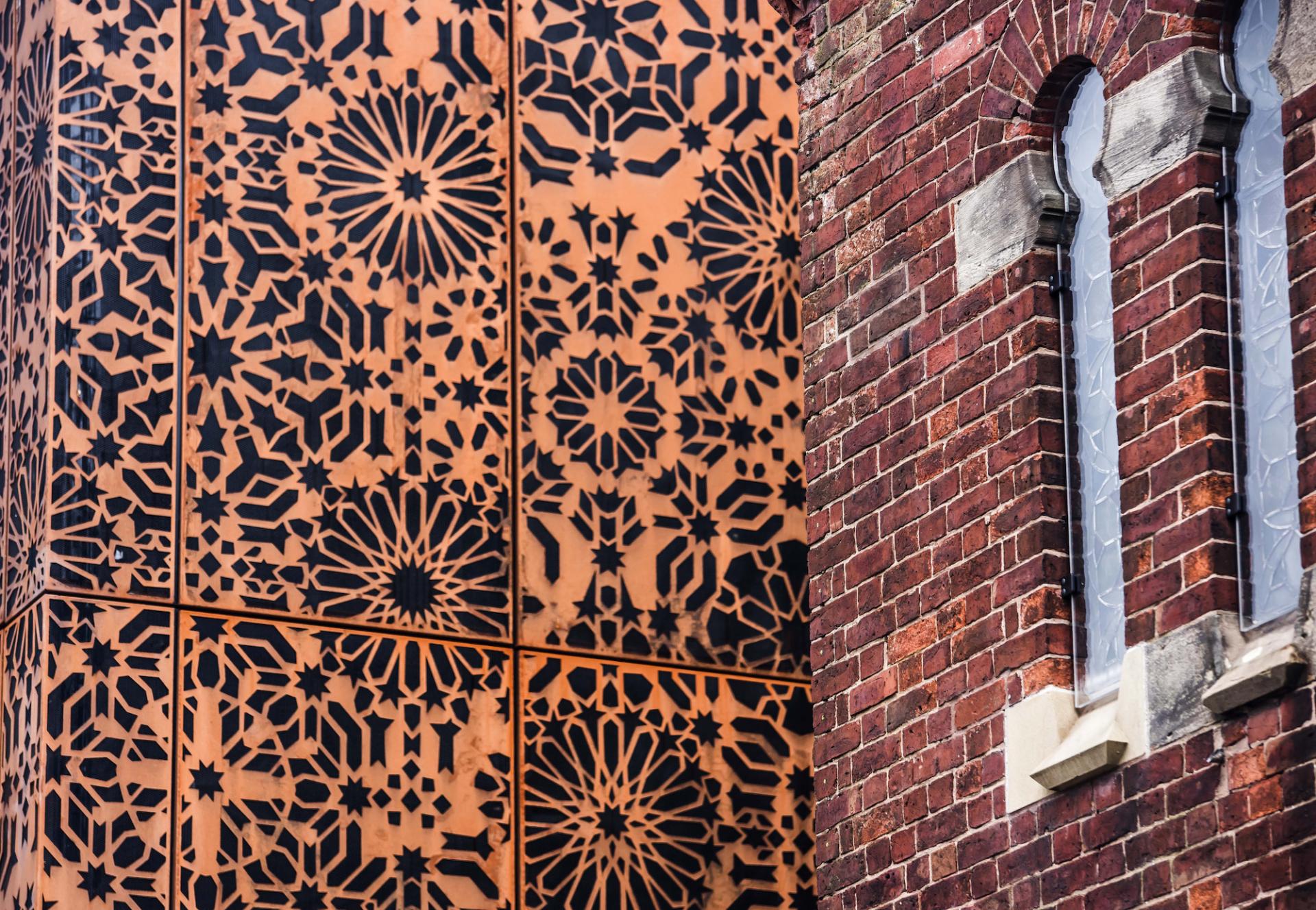 Corten steel facade of Manchester Jewish Museum contrasted with intricate brick detailing and stained glass windows.