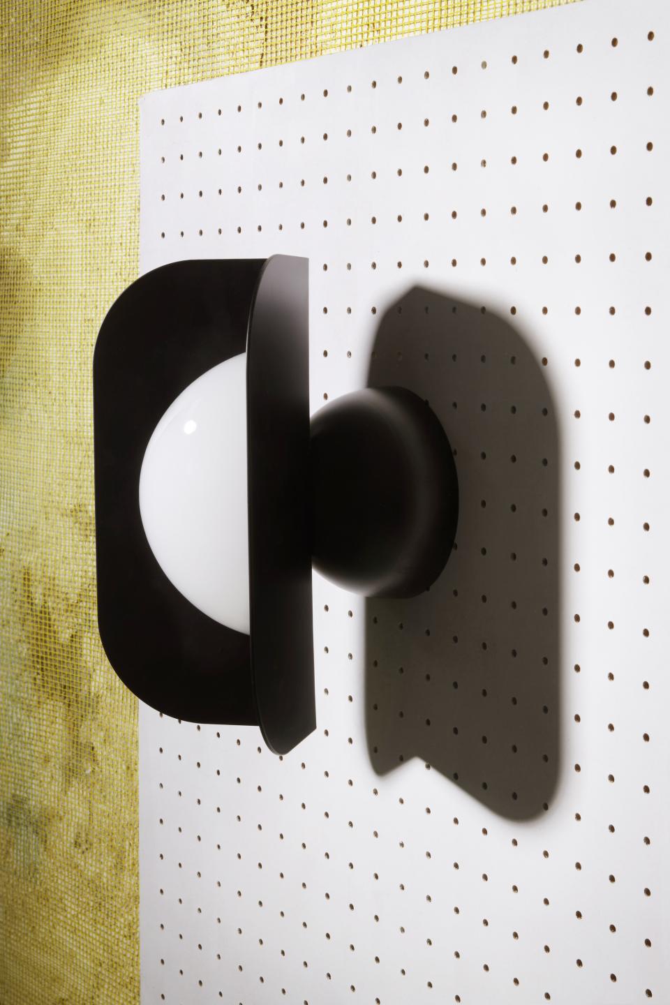 Sculptural black and white lamp design against a textured yellow background, showcasing Serena Confalonieri's innovative interior style.