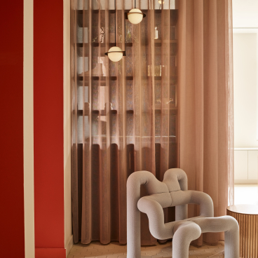 Modern interior of Liberty House showcasing a unique sculptural chair, warm tones, soft curtains, and stylish lighting in London.