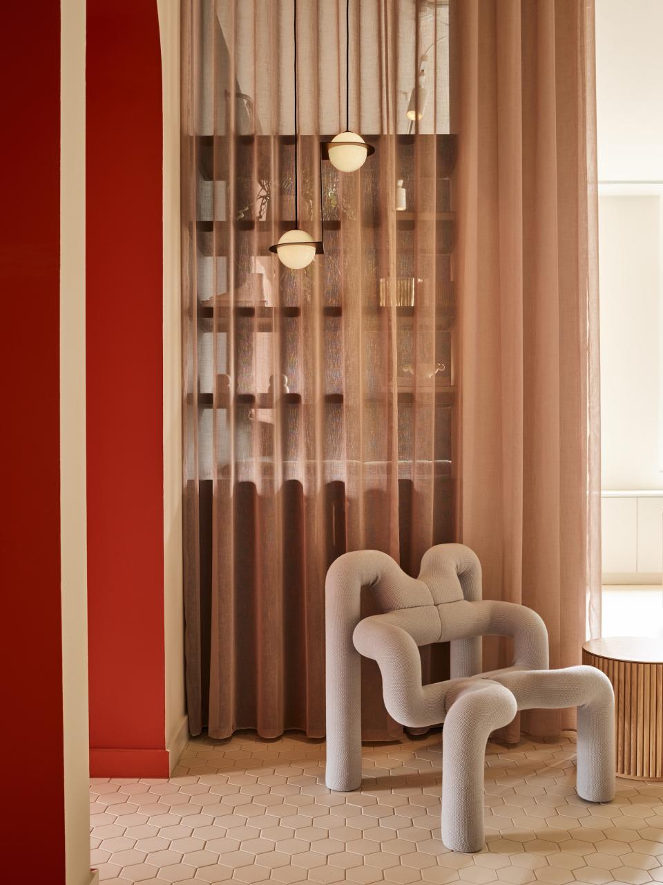 Modern interior of Liberty House showcasing a unique sculptural chair, warm tones, soft curtains, and stylish lighting in London.