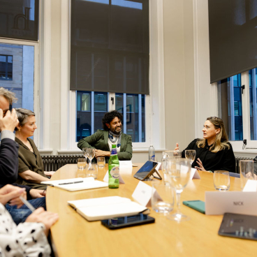 Discussion on Glasgow's property market among professionals in a seminar setting, featuring diverse participants at a conference table.
