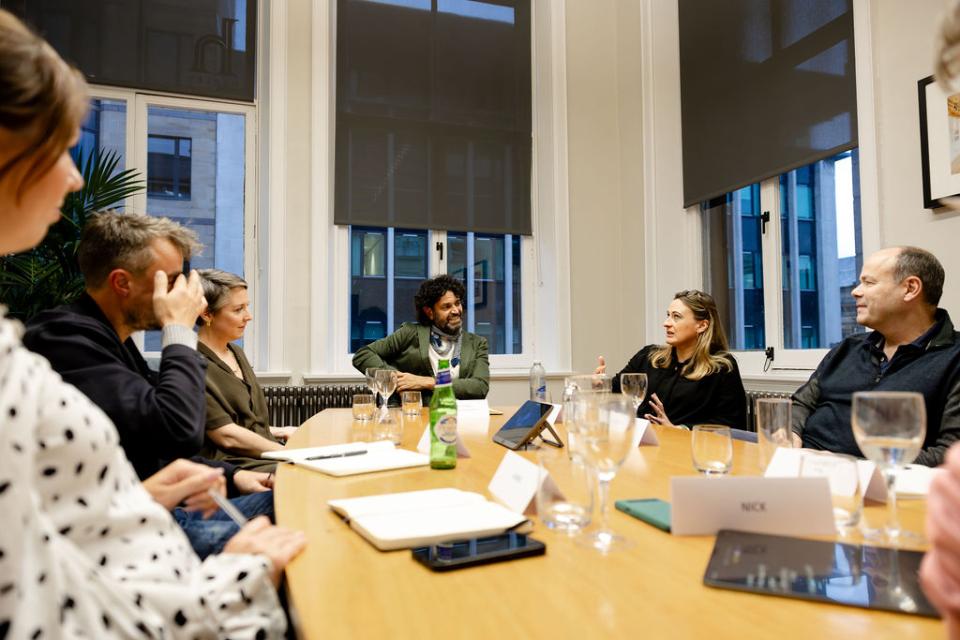 Discussion on Glasgow's property market among professionals in a seminar setting, featuring diverse participants at a conference table.