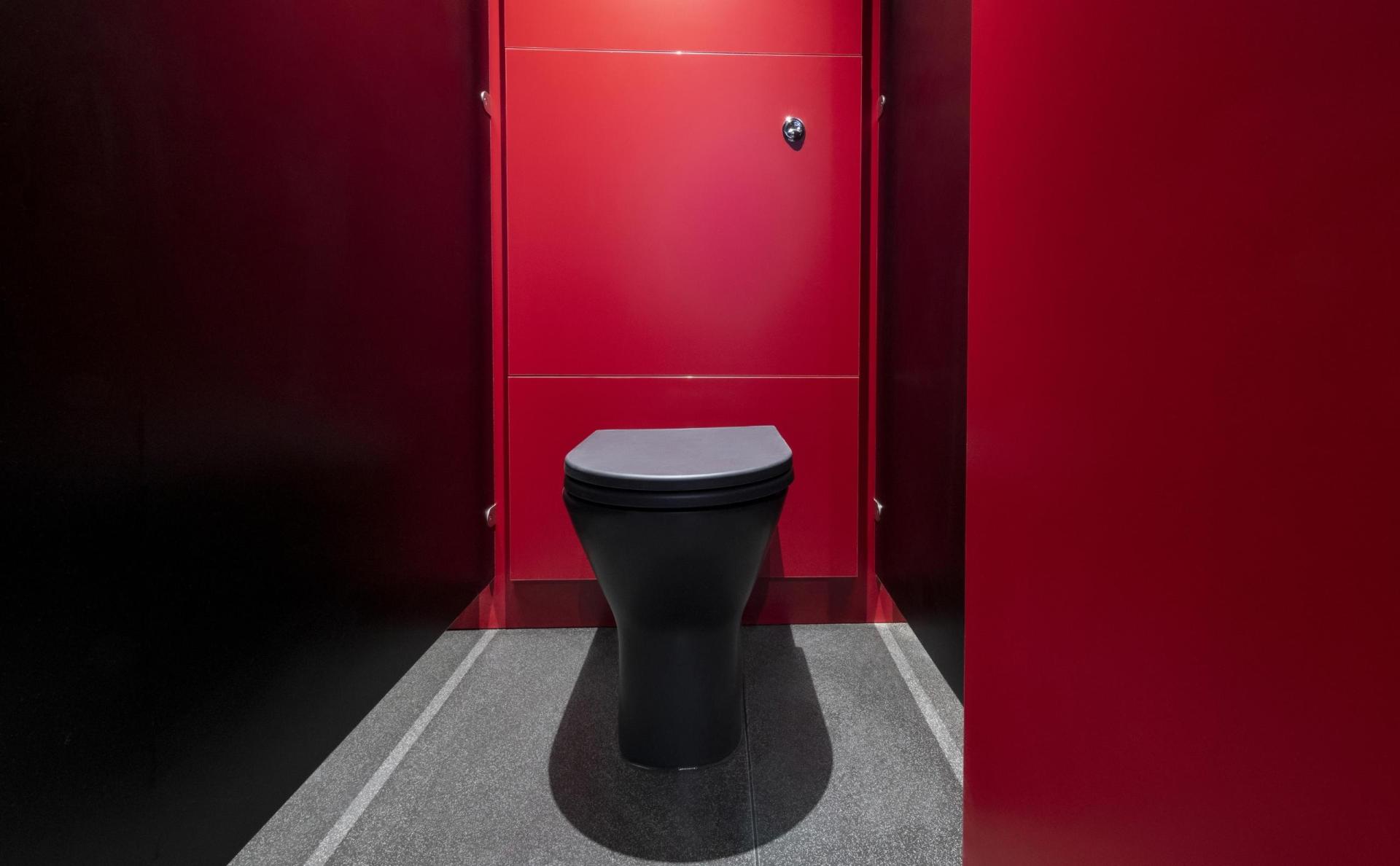 Modern restroom featuring a sleek black toilet against vibrant red walls, reflecting 2023 interior color trends.