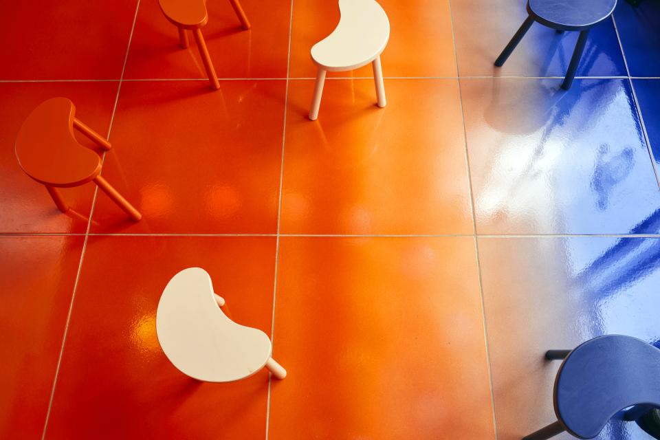 Colorful, playful stools on a vibrant gradient floor in Café Nuances, showcasing psychedelic disco decor by Studio Uchronia.