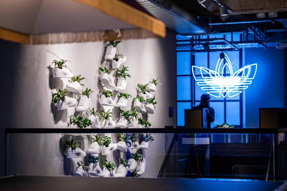 A wall display featuring white sneakers integrated with greenery at Adidas' sustainable flagship store in London.