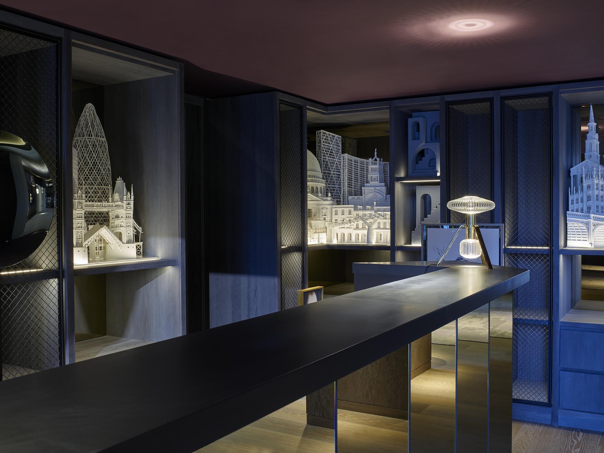 Elegant hotel reception with intricate architectural models, showcasing Yabu Pushelberg's dramatic design in Leicester Square.