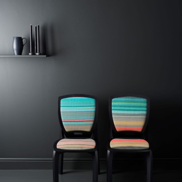 Scandinavian design chairs with vibrant woven patterns against a dark wall, highlighting contemporary aesthetics for Decorex International.